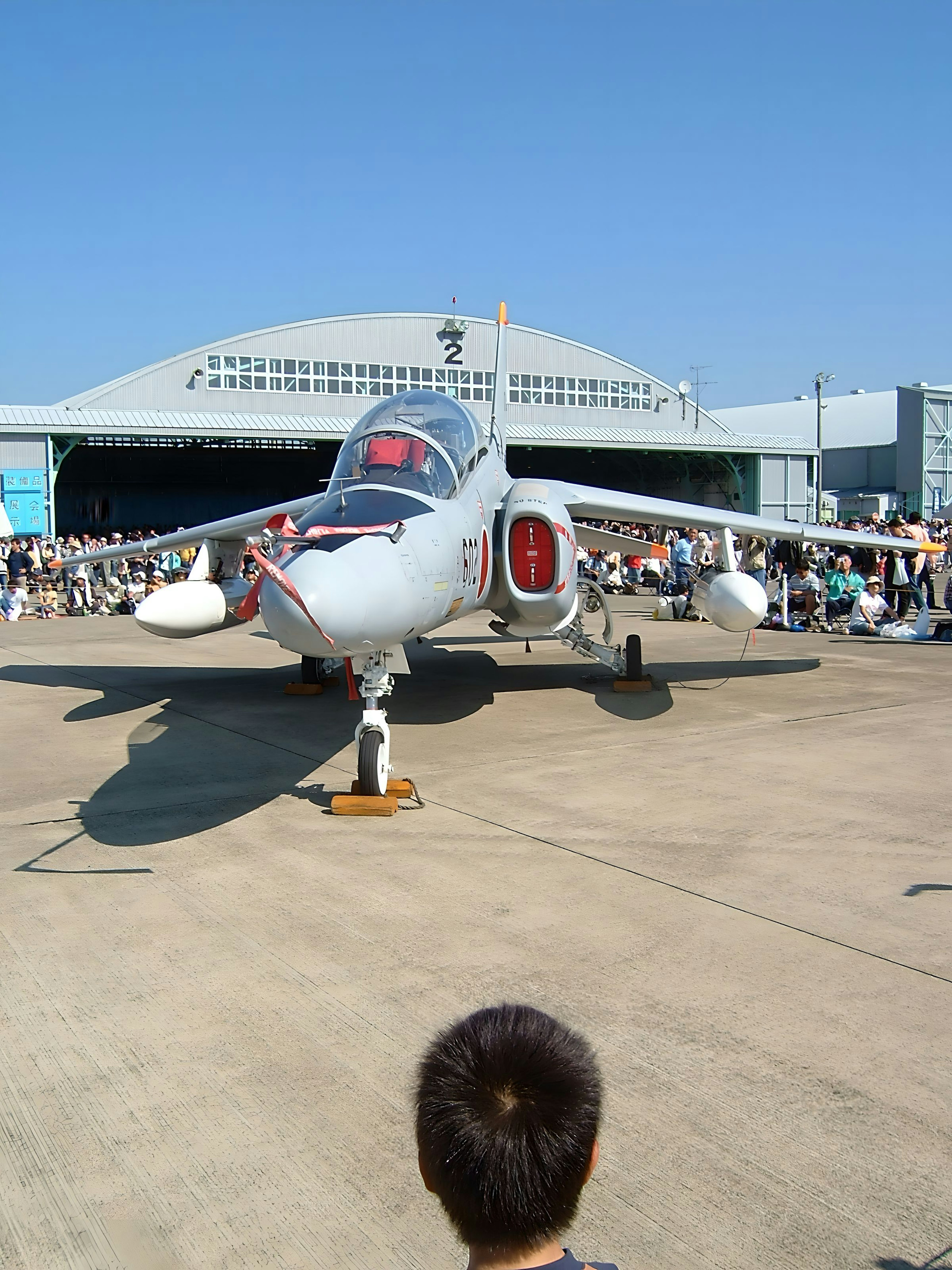 Un avion de chasse exposé lors d'un salon aéronautique entouré de spectateurs