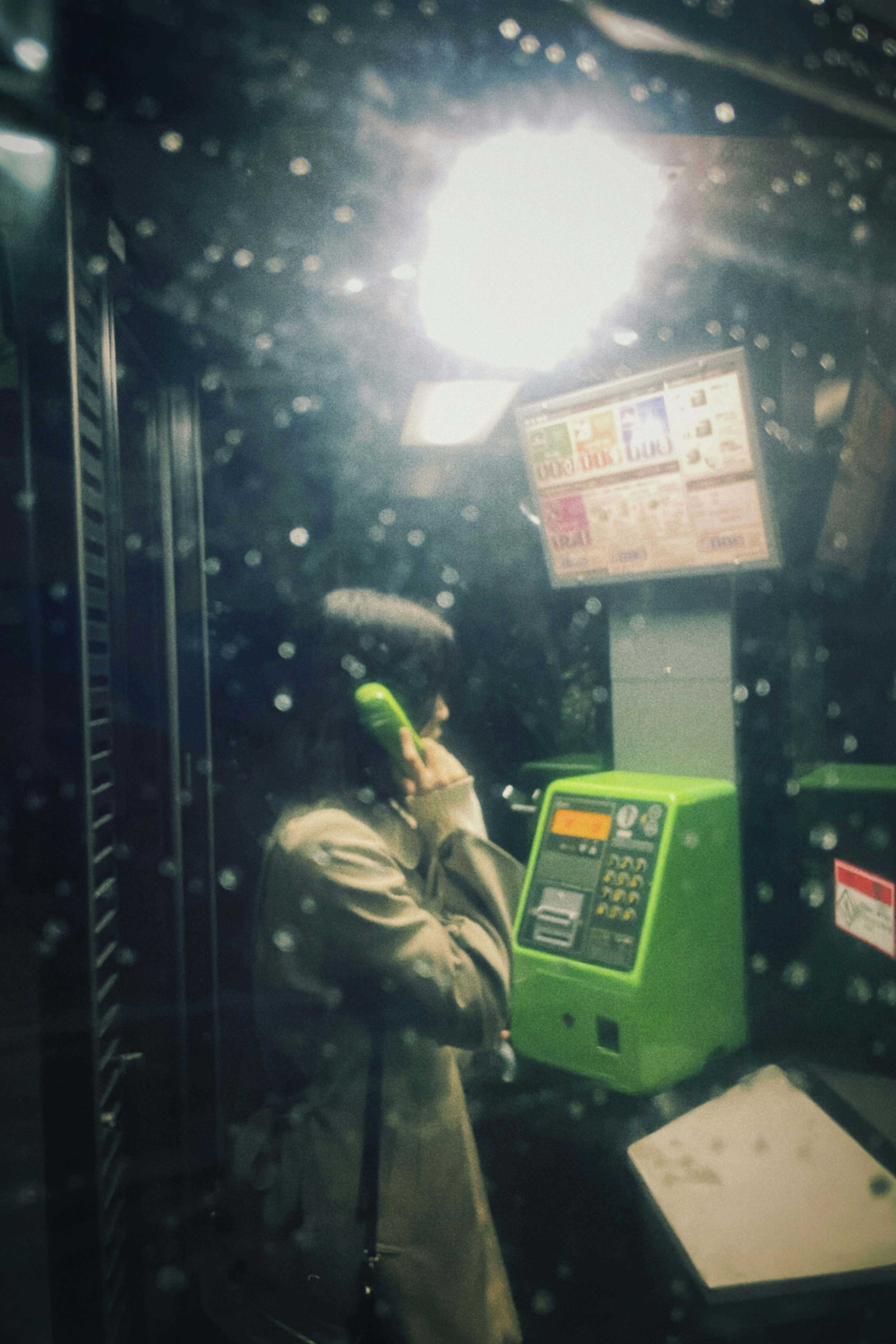 A person on the phone in a dimly lit public phone booth