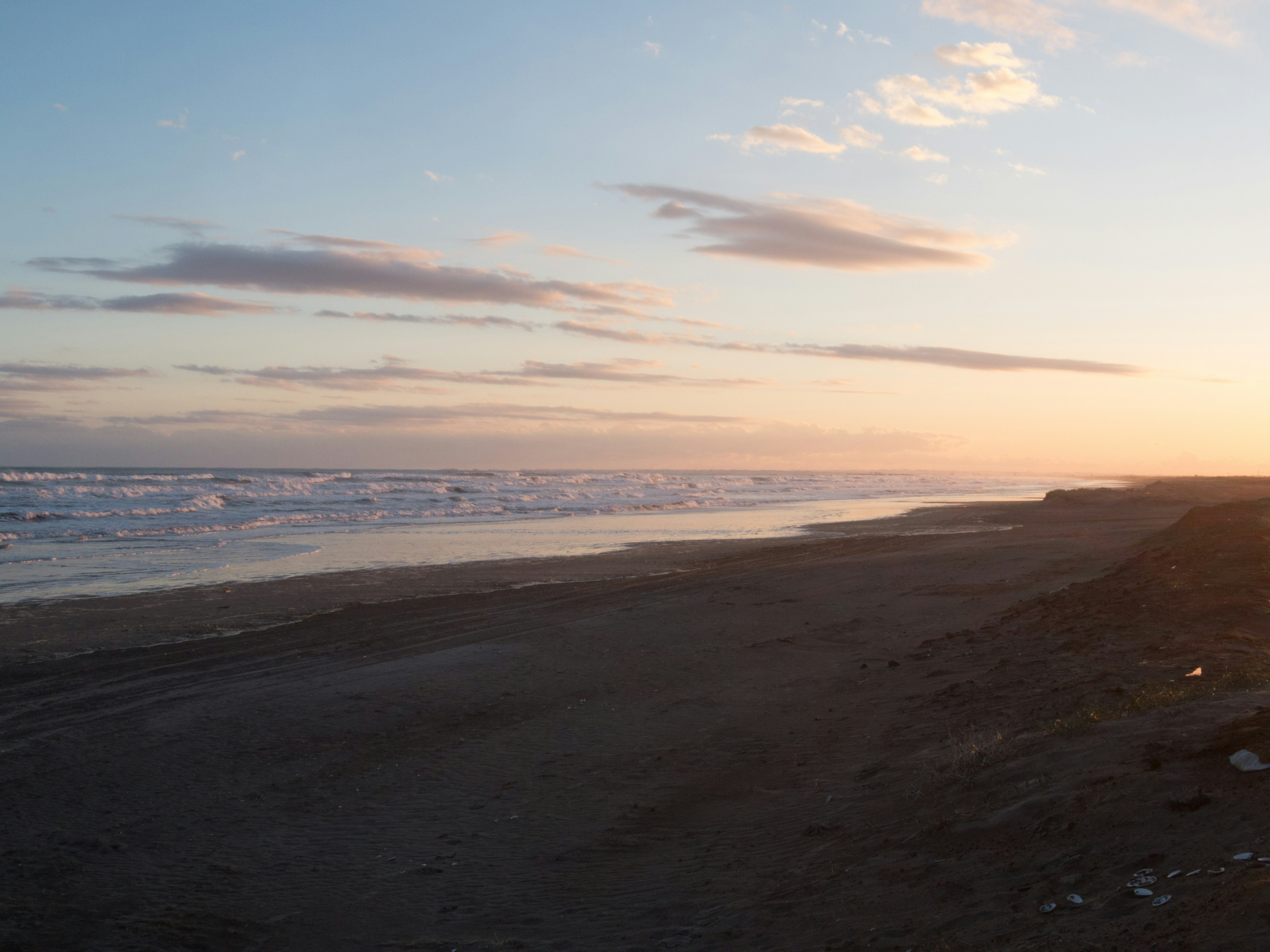 Vista de playa escénica al atardecer con olas y nubes