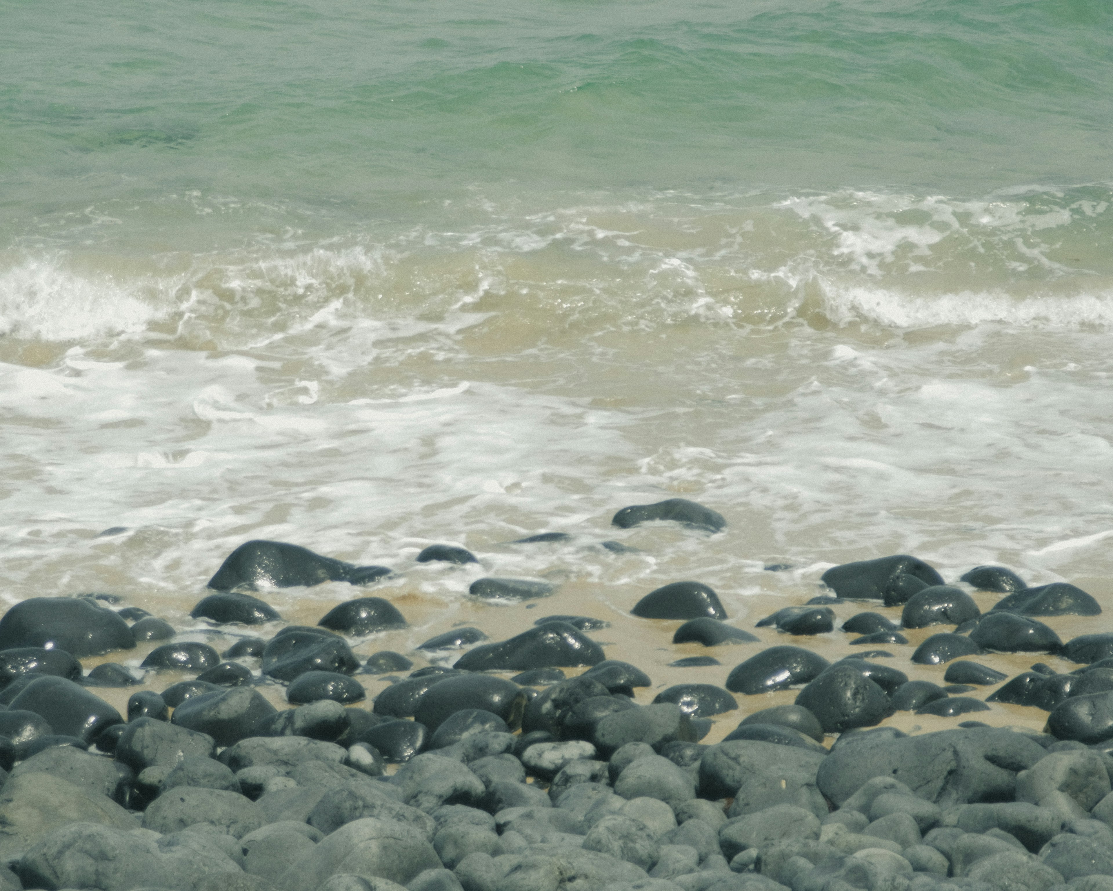 海滩场景，波浪和黑色卵石