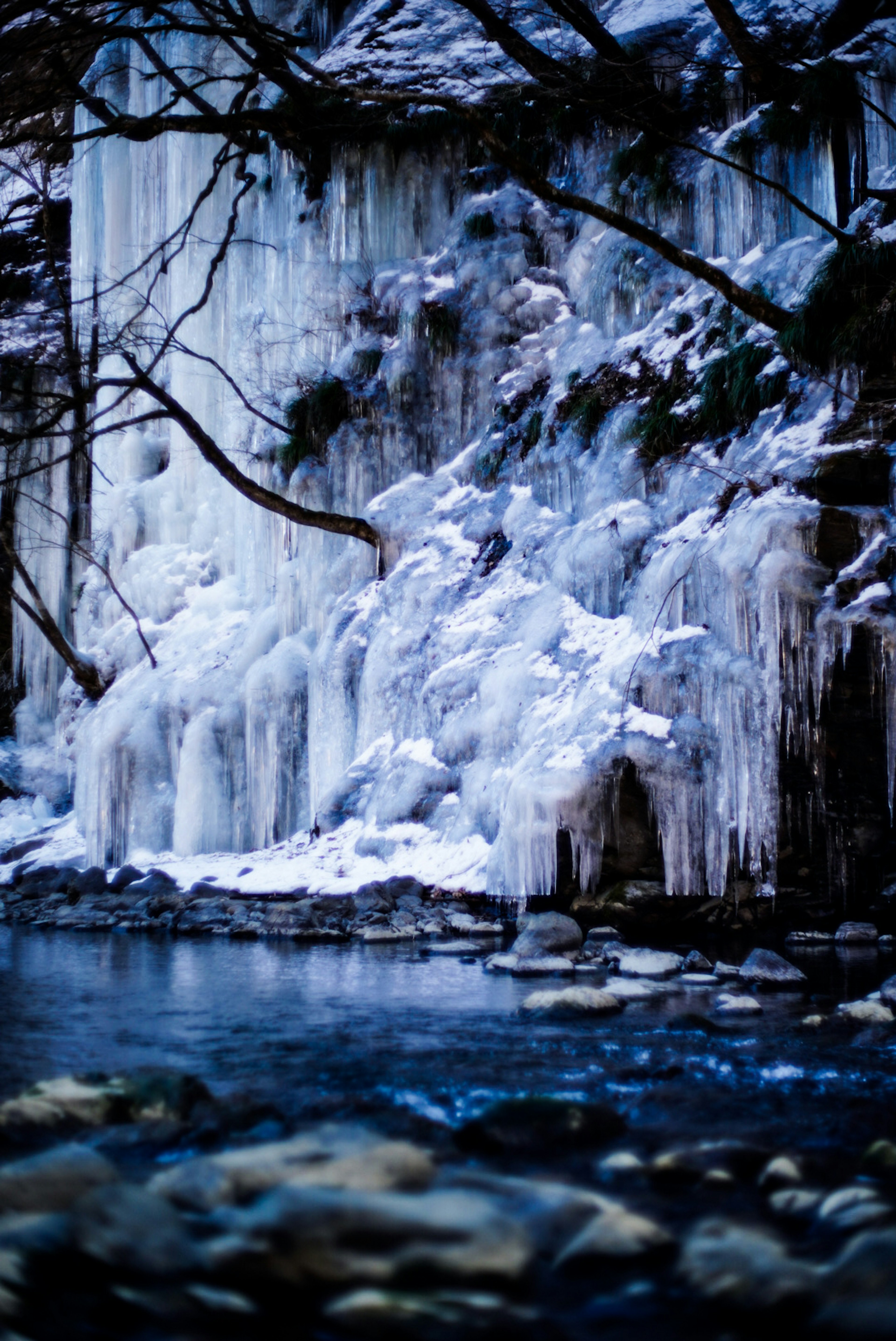 Scenario invernale con una cascata di ghiaccio e acqua blu che scorre