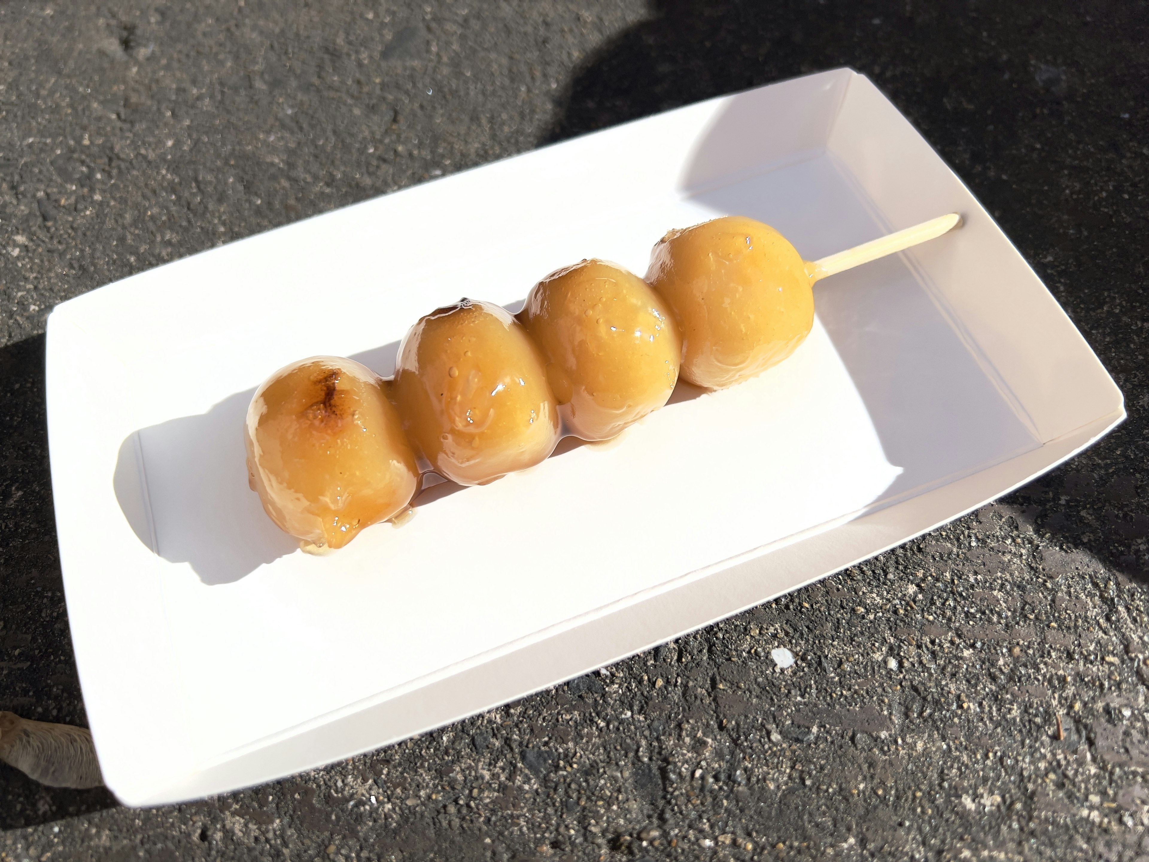 Four sweet dumplings on a skewer served on a white plate