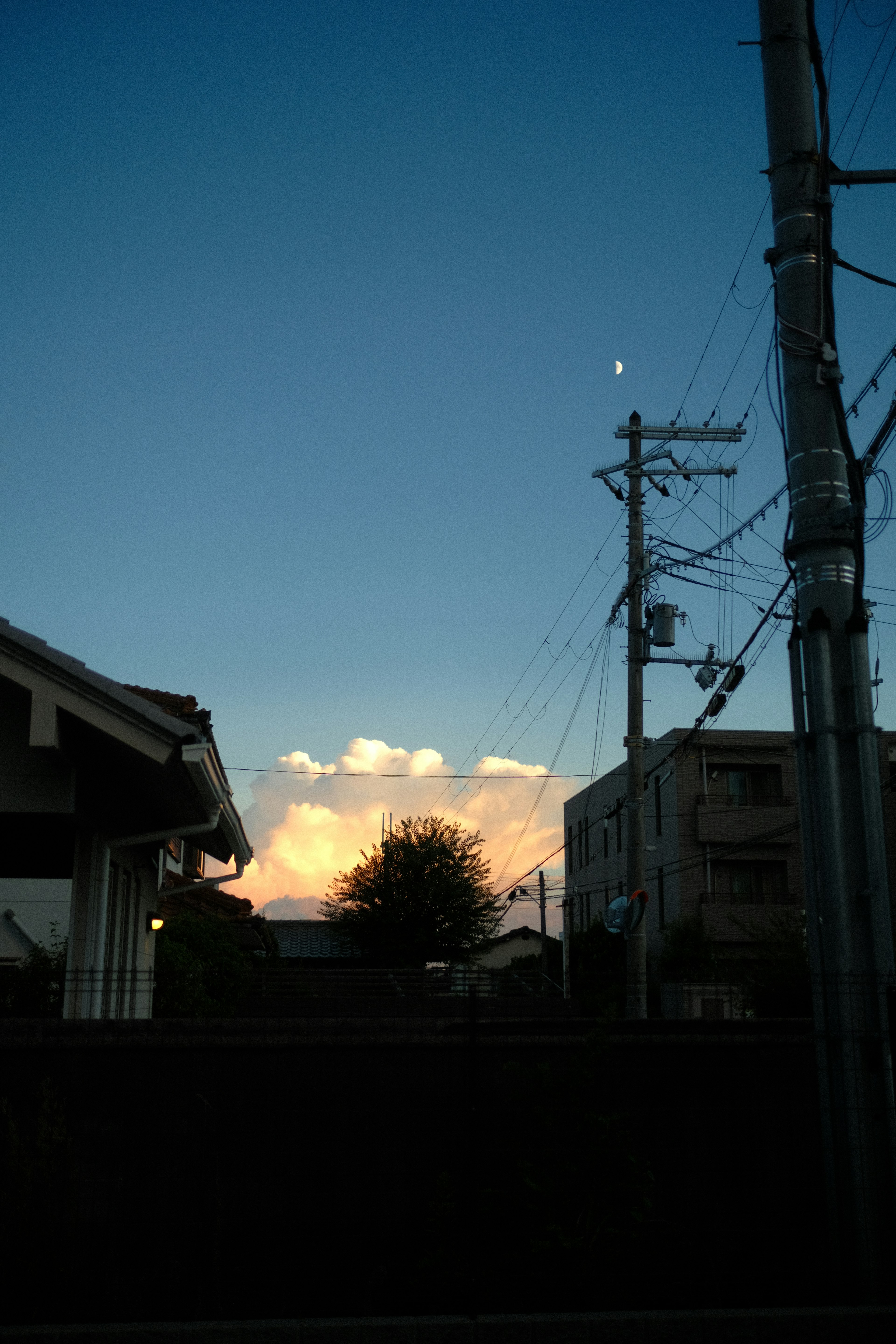 Langit malam tenang dengan bulan terlihat dan awan oranye