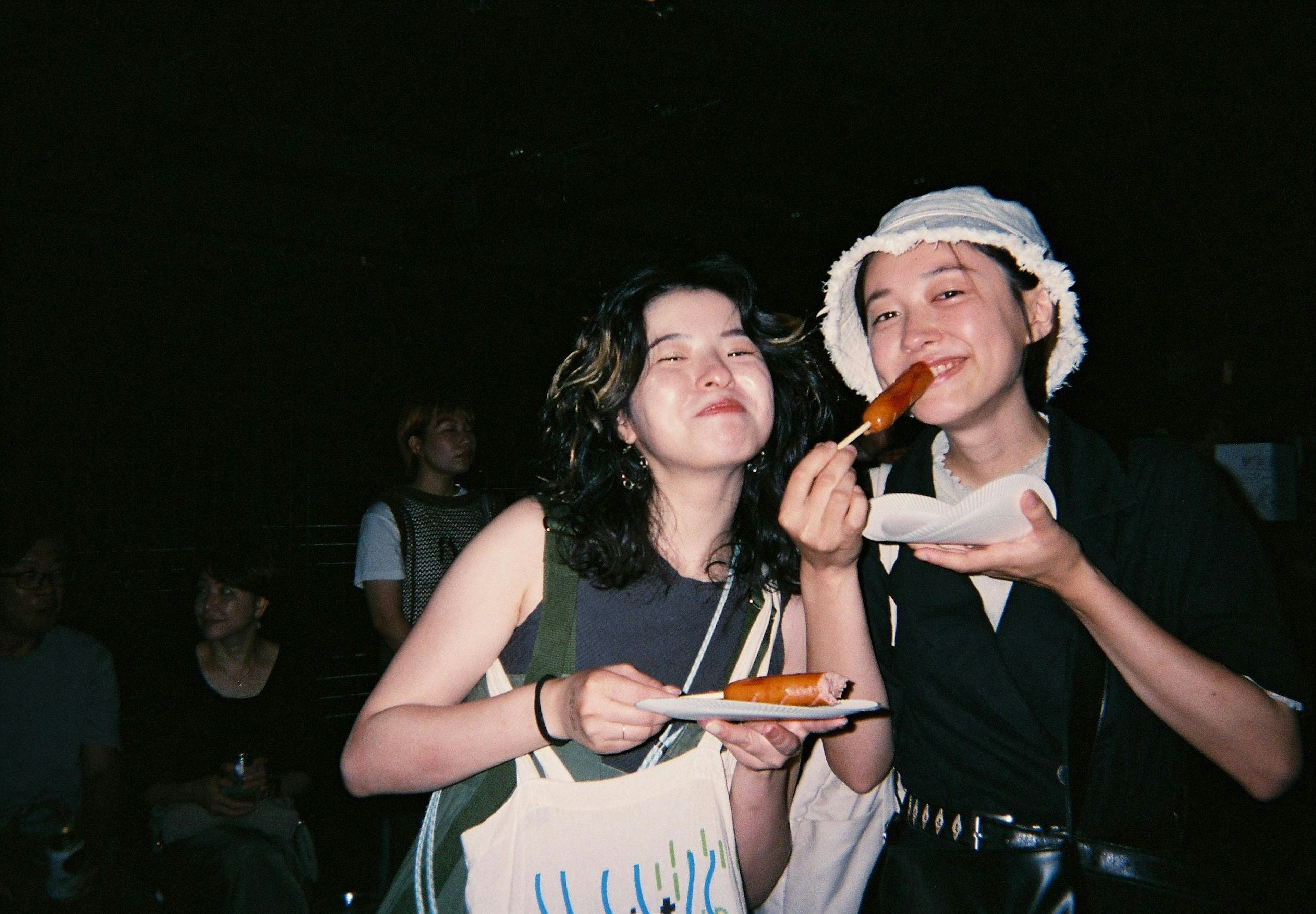 Two women happily eating food in a dark background photo