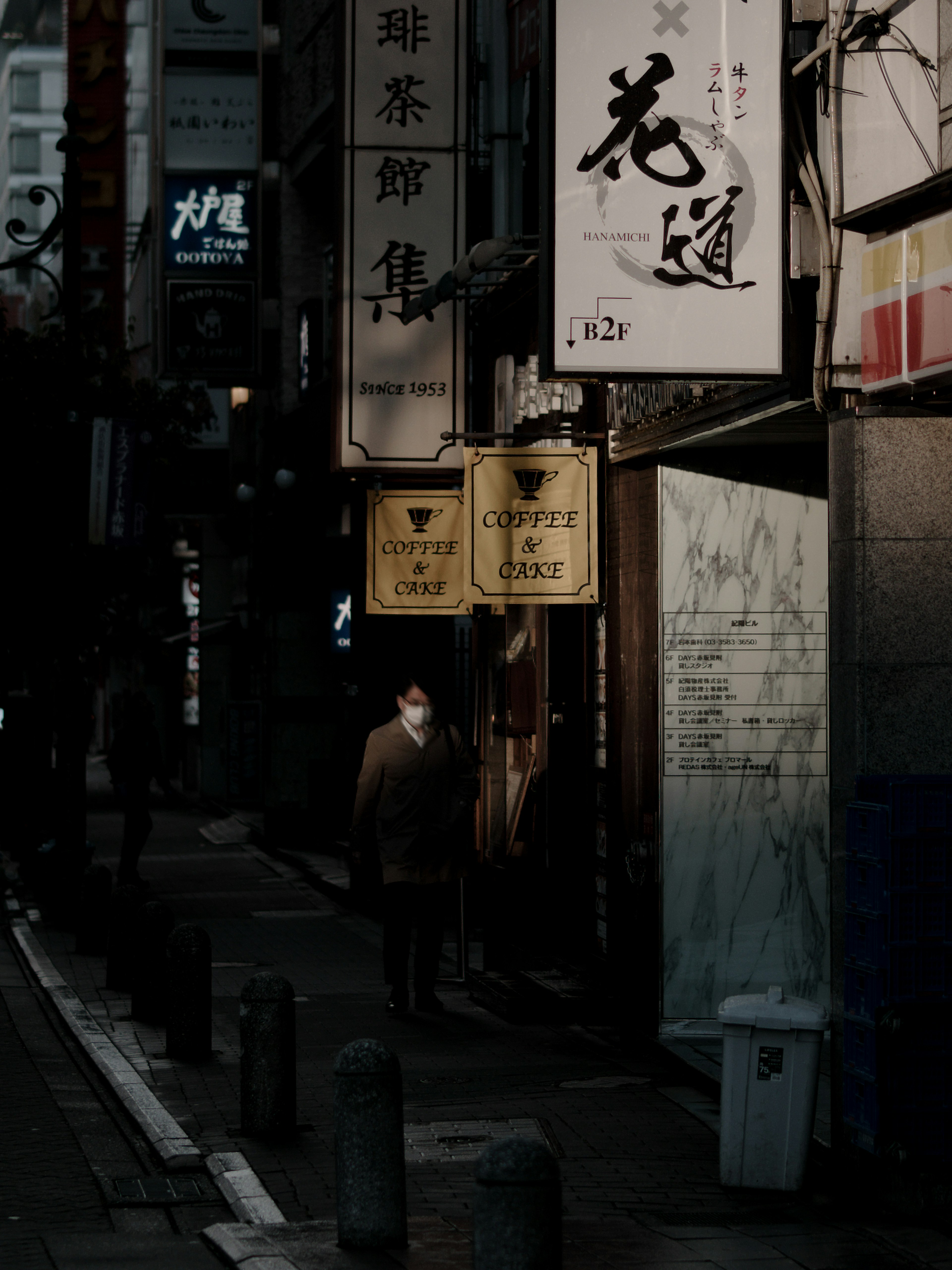 A person standing in a dim alley with old storefront signs