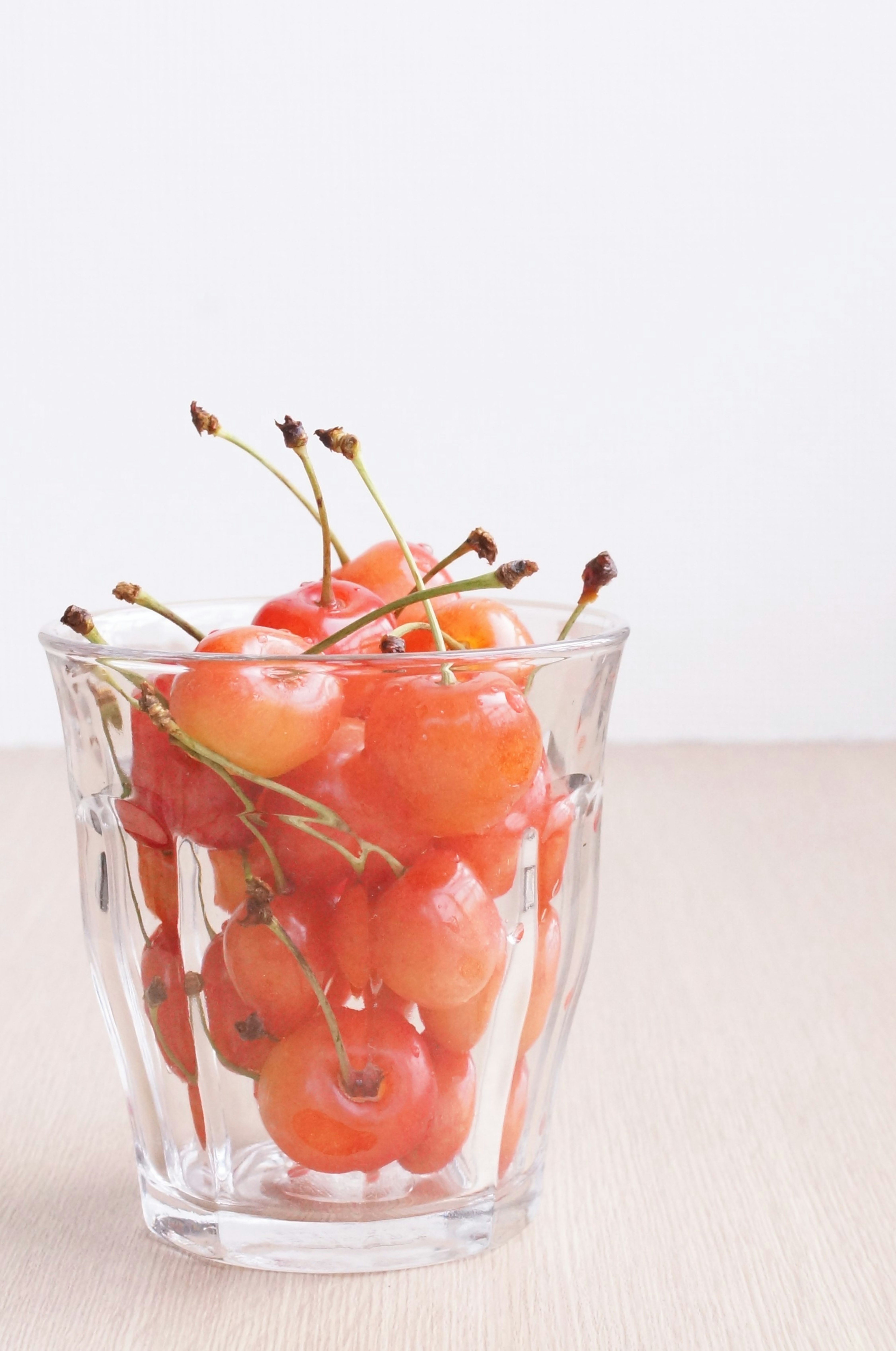 Lebhafte orangefarbene Kirschen in einem klaren Glasbecher