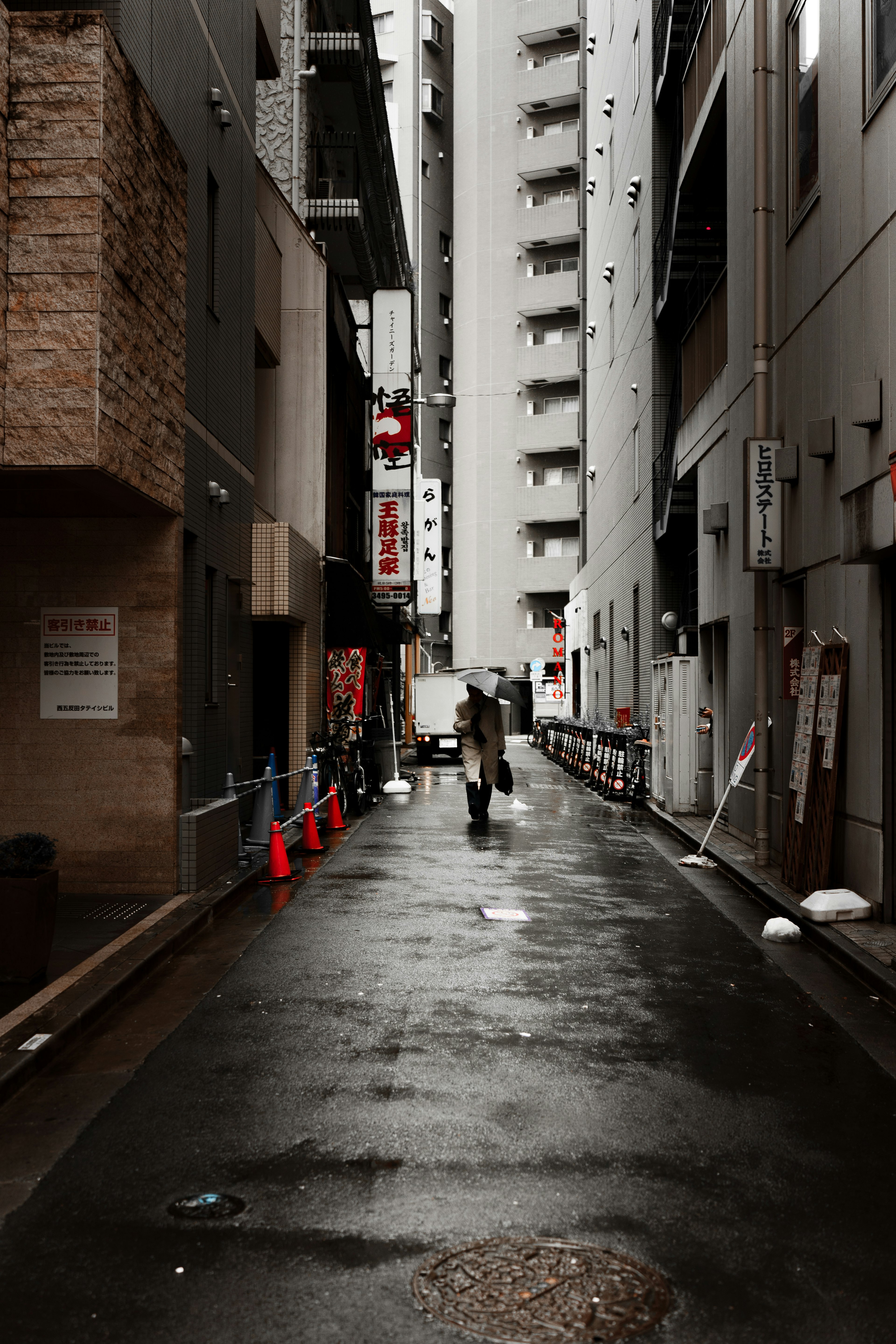 A person walking in a narrow alleyway with wet pavement