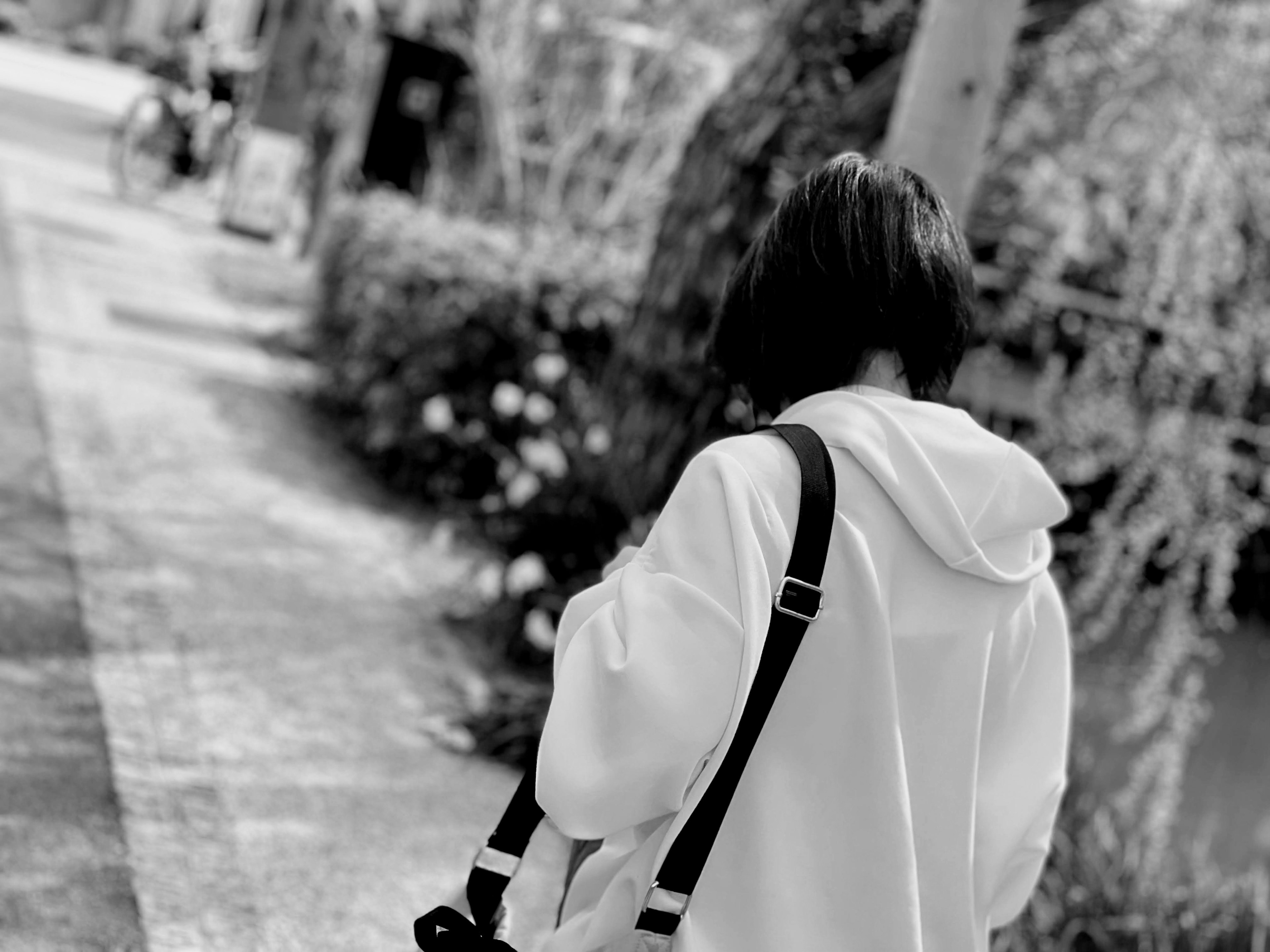 Une femme portant un sweat à capuche blanc marchant de dos dans une photo en noir et blanc