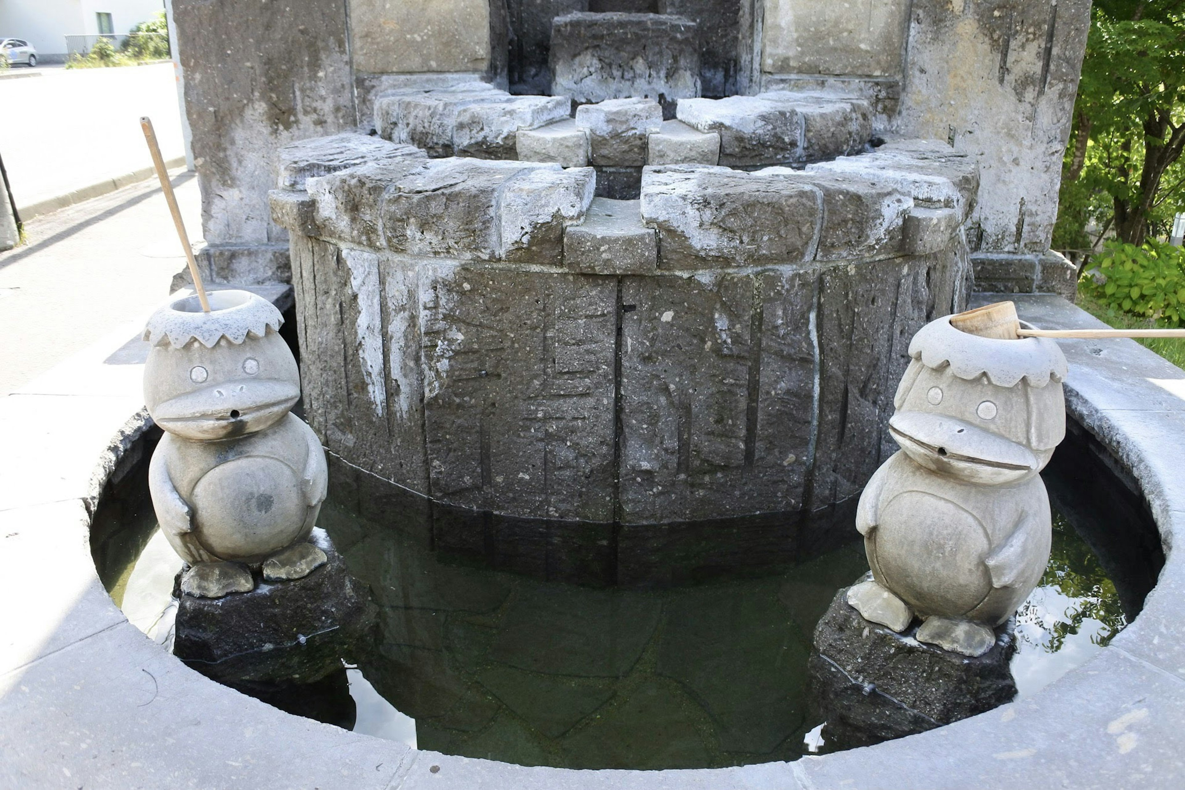 Dos estatuas de piedra adorables al lado de una fuente con tallados intrincados