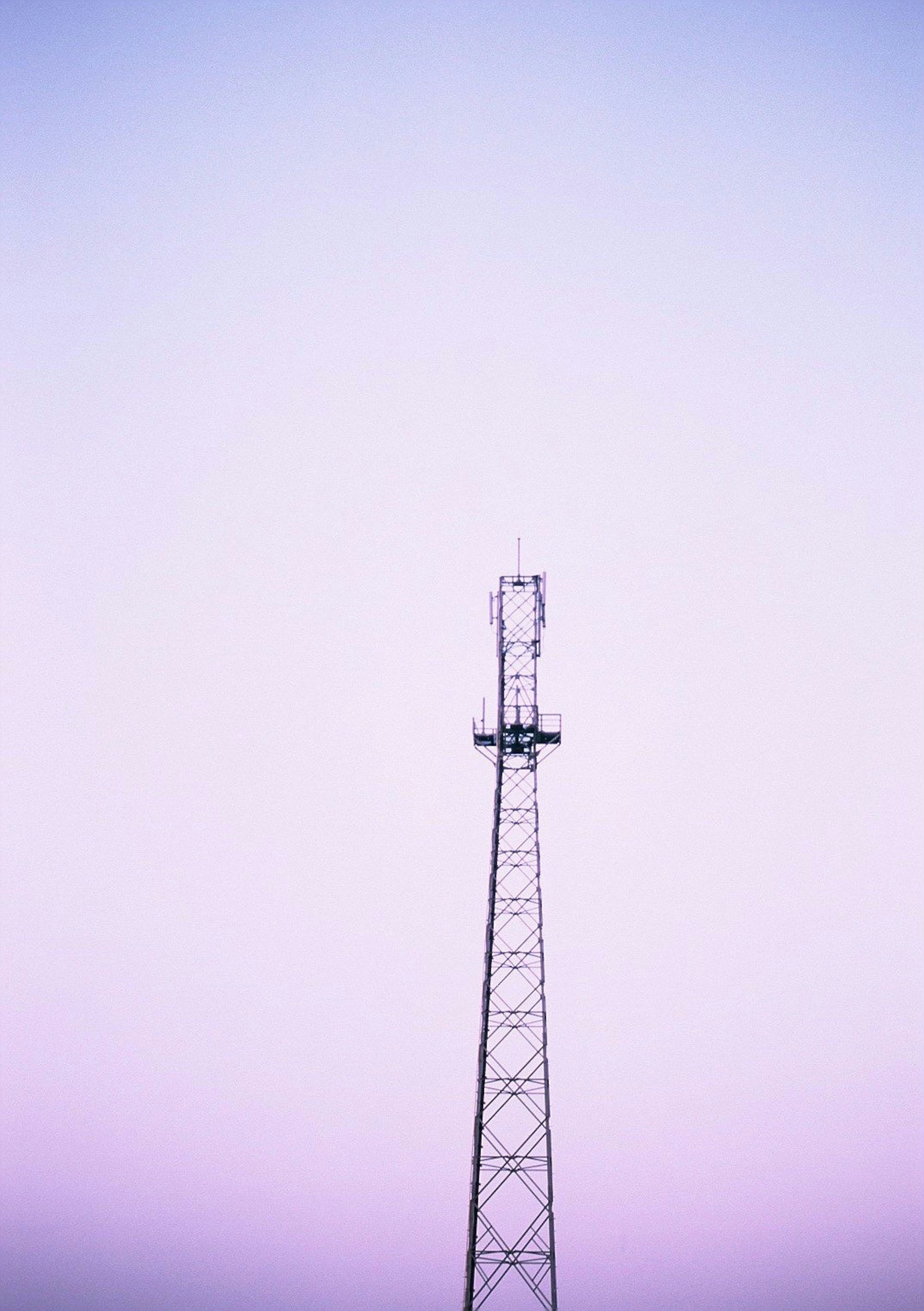 Siluet menara komunikasi di latar belakang langit ungu