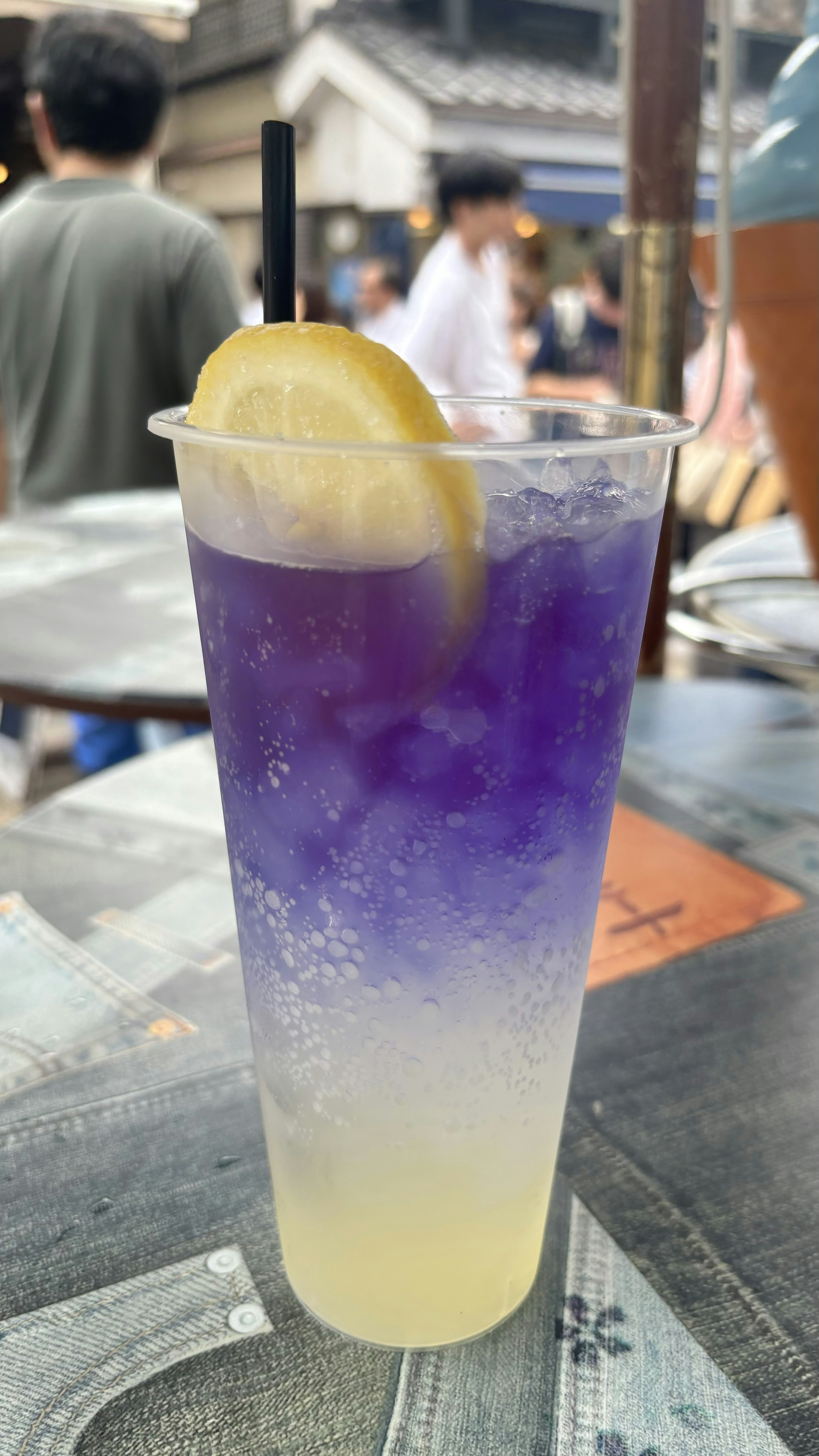 A cup of gradient purple and white drink topped with a slice of lemon