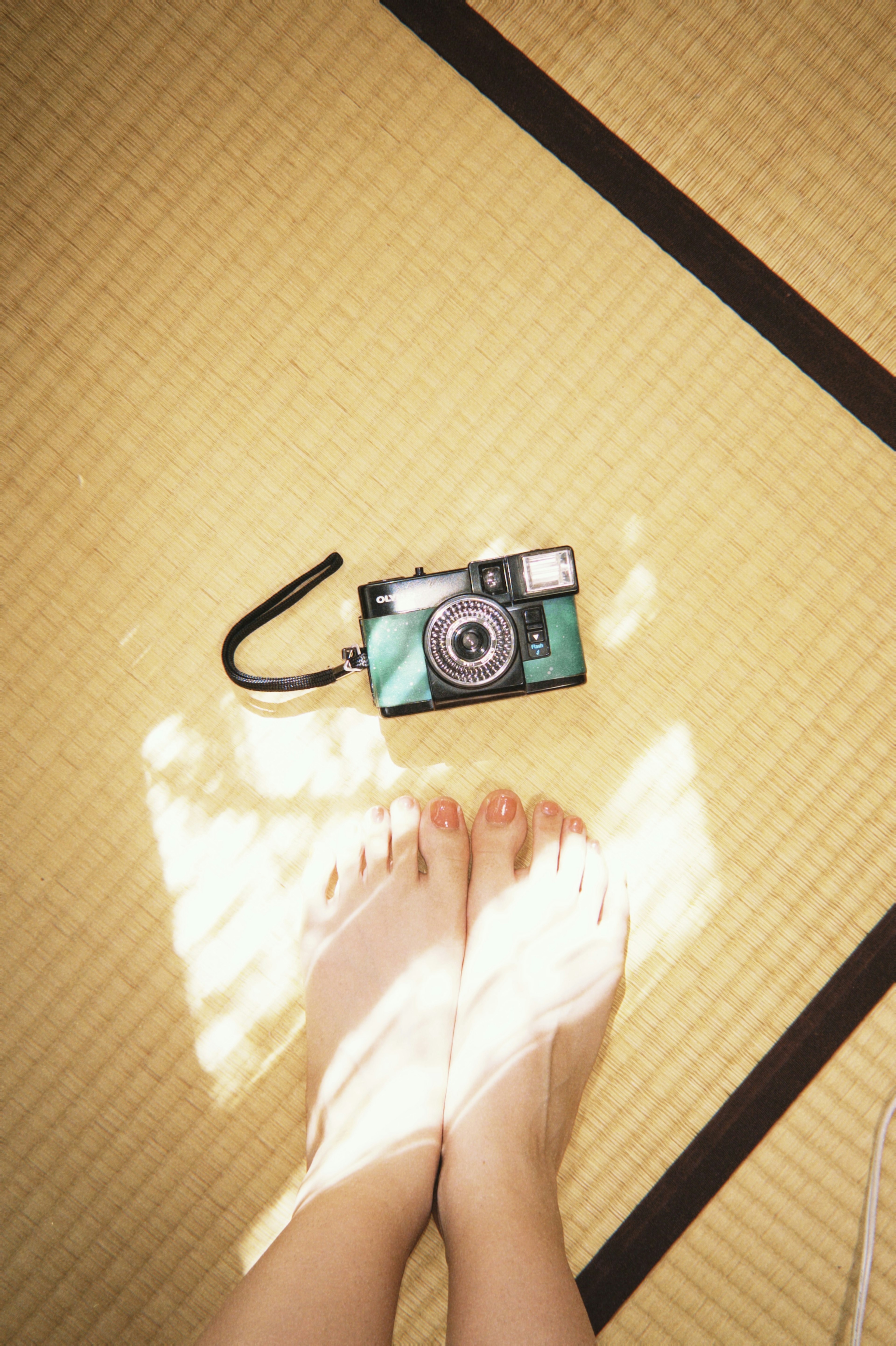 Macchina fotografica posata su tatami con piedi nudi in vista