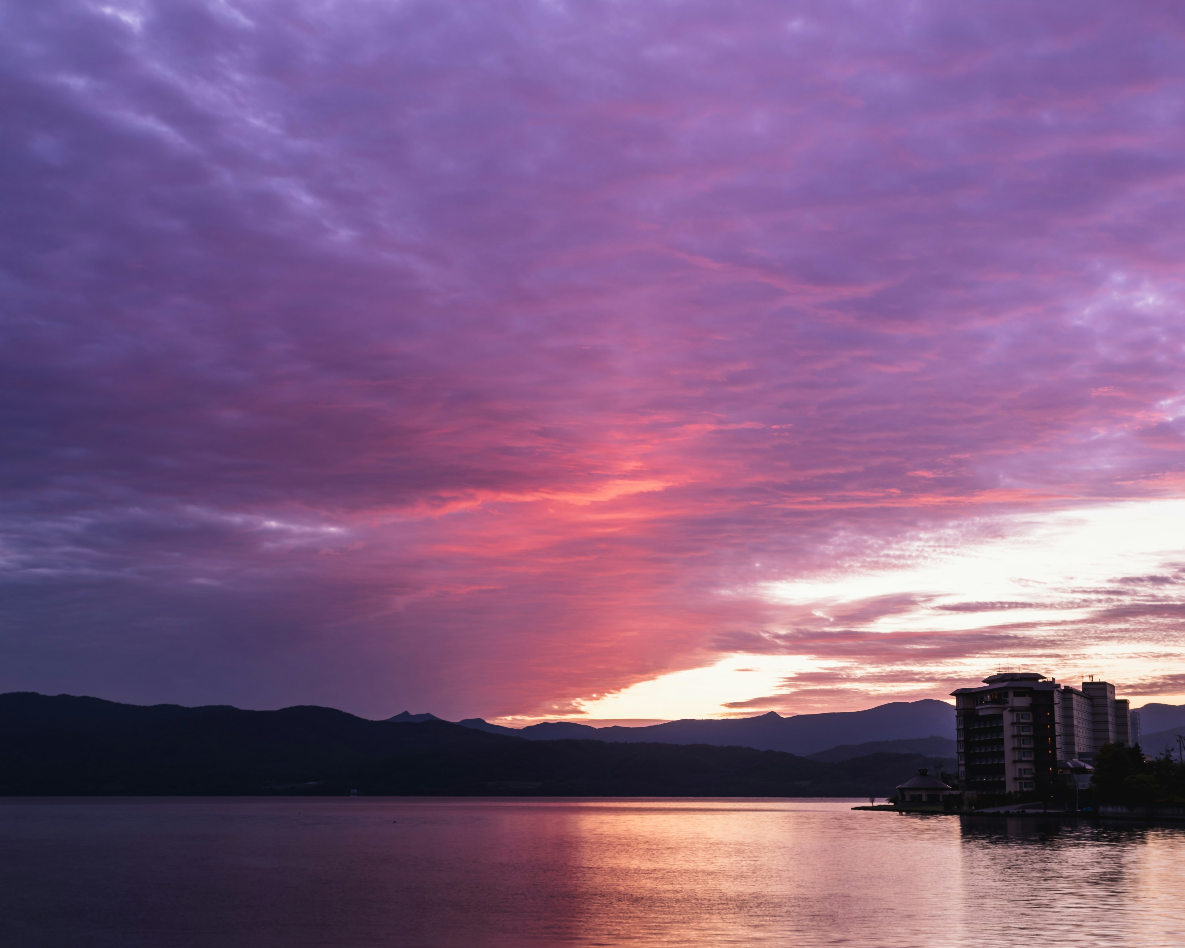 Cielo de atardecer con nubes moradas sobre un lago tranquilo