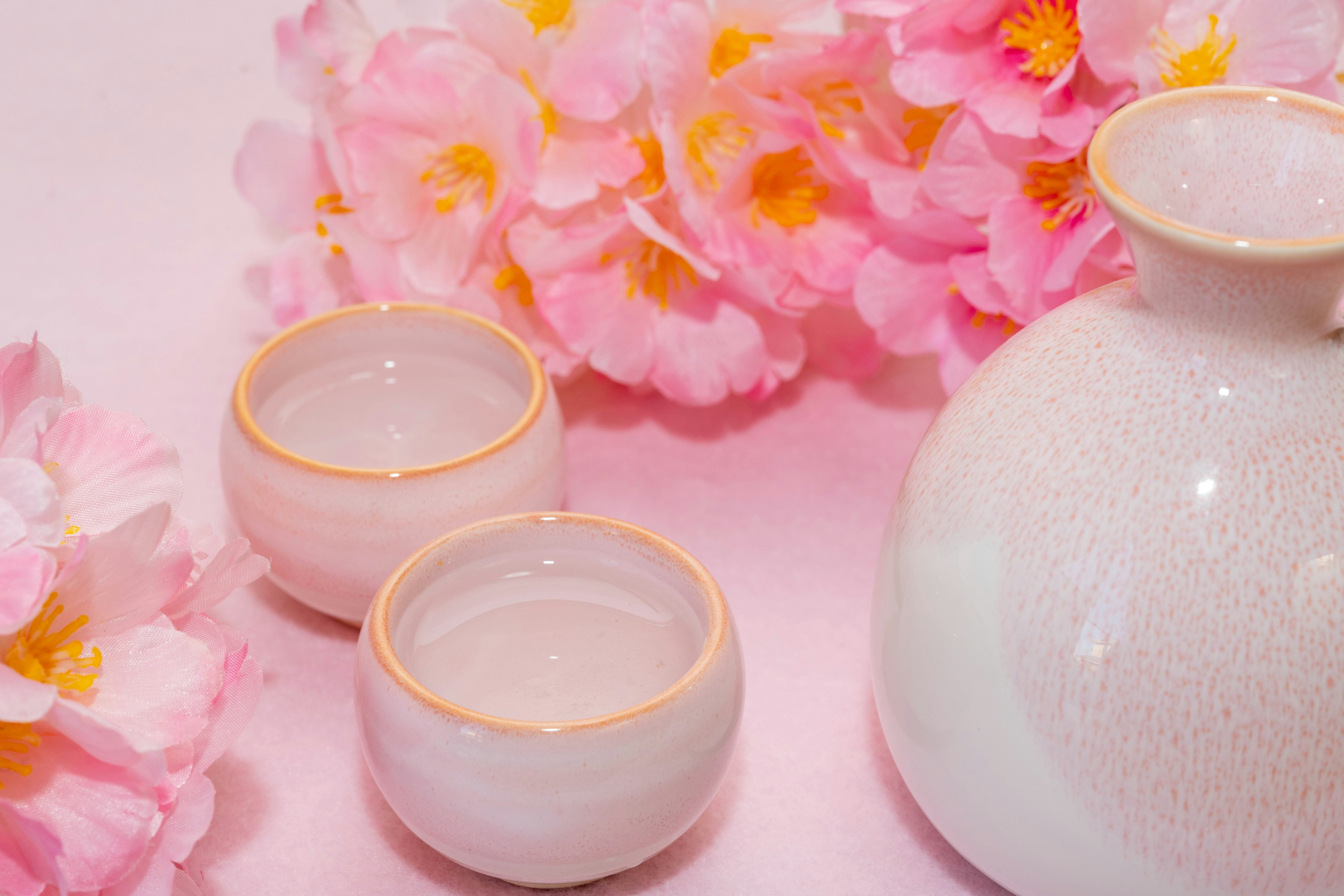 Arrangement magnifique avec des fleurs roses, un vase en céramique blanche et deux petites tasses