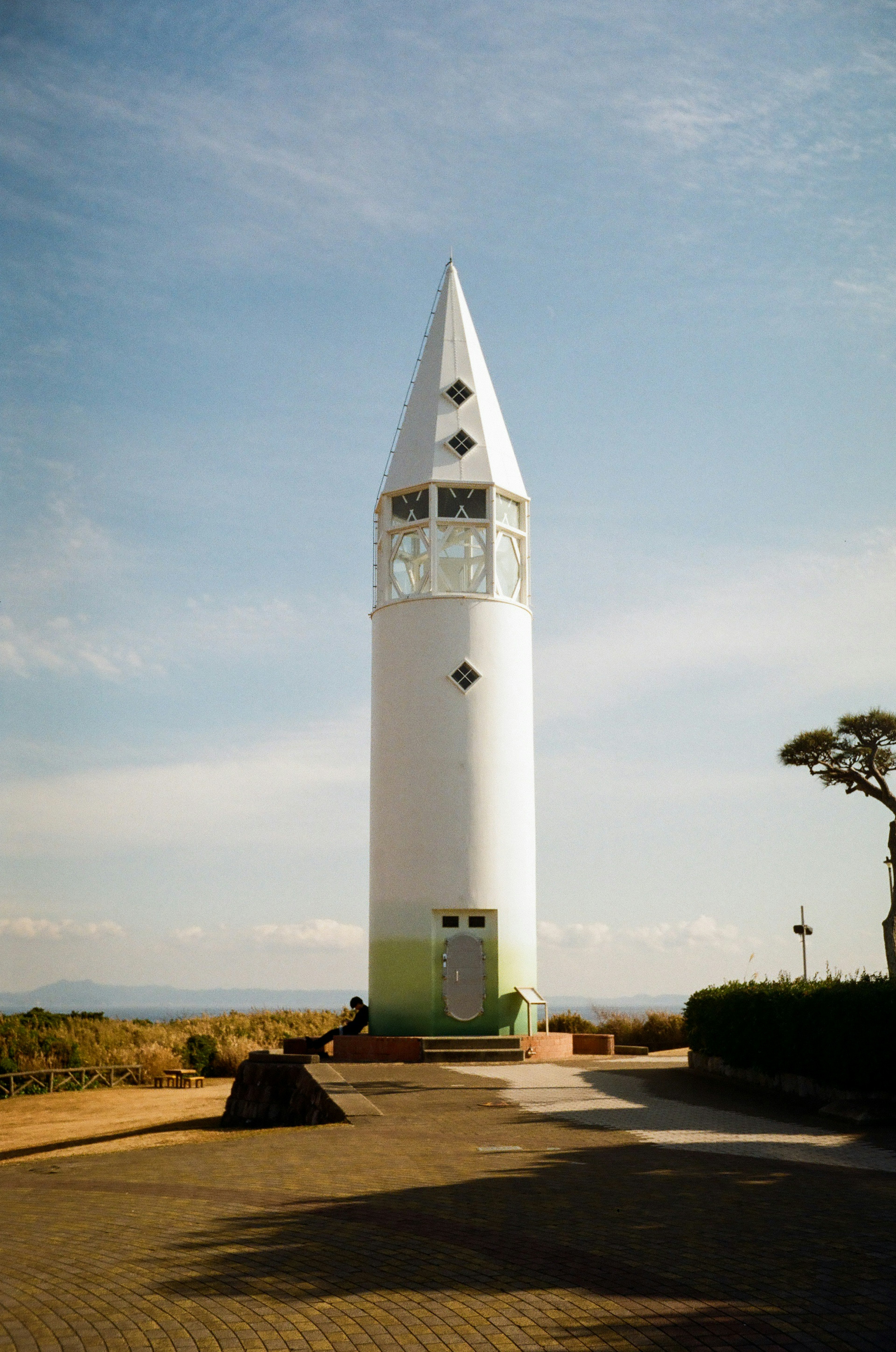 A white tower with a pointed roof under a blue sky