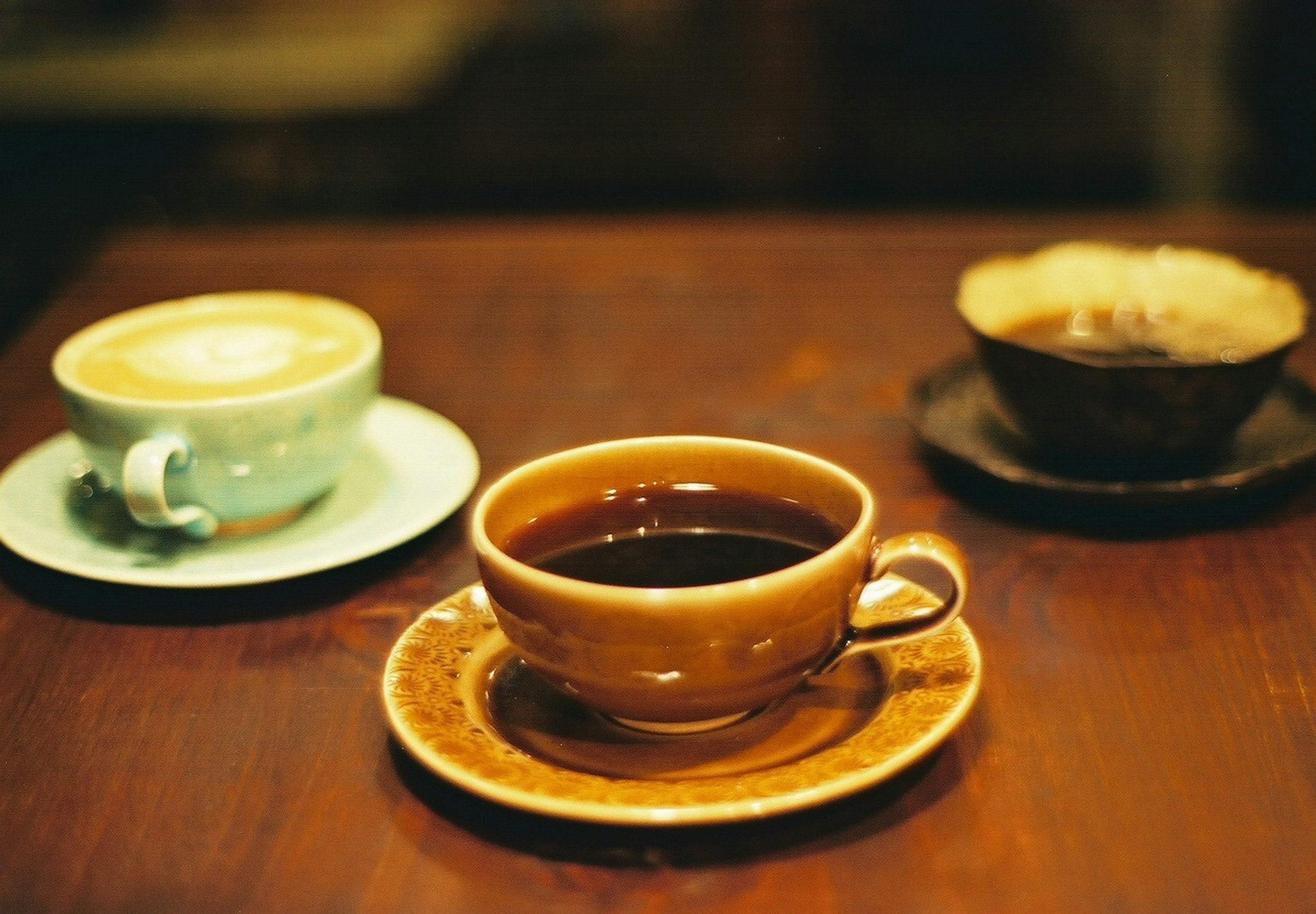 Un conjunto de tazas de café sobre una mesa de madera con una bebida oscura y una bebida clara