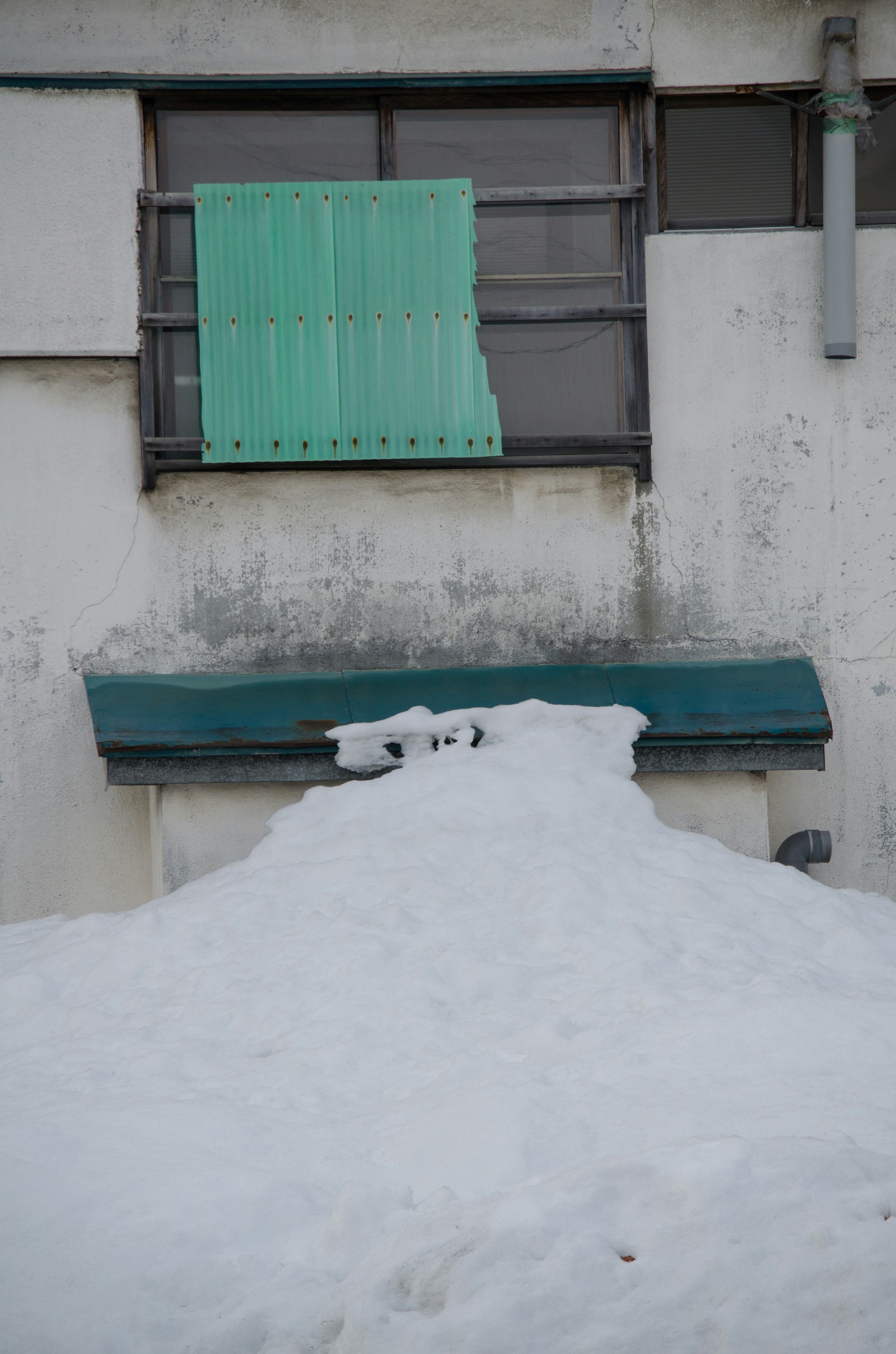 雪に覆われた窓と緑のブラインドのある壁