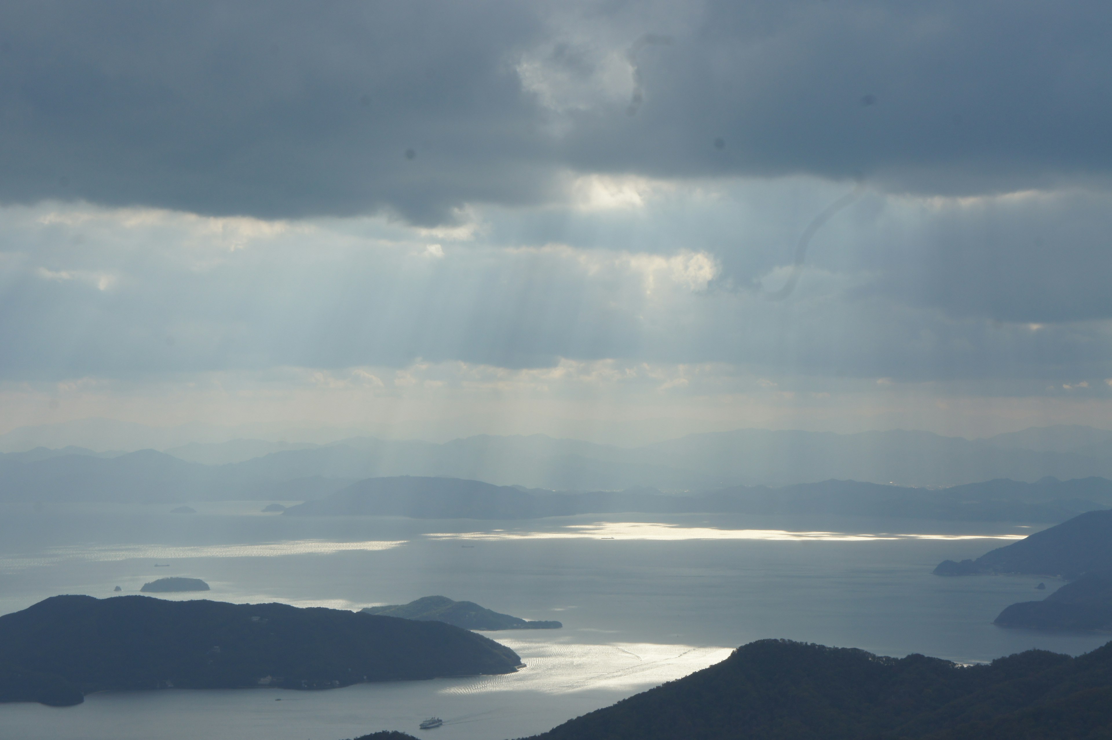 Vista maestosa del mare dalla montagna raggi di luce che attraversano il cielo nuvoloso