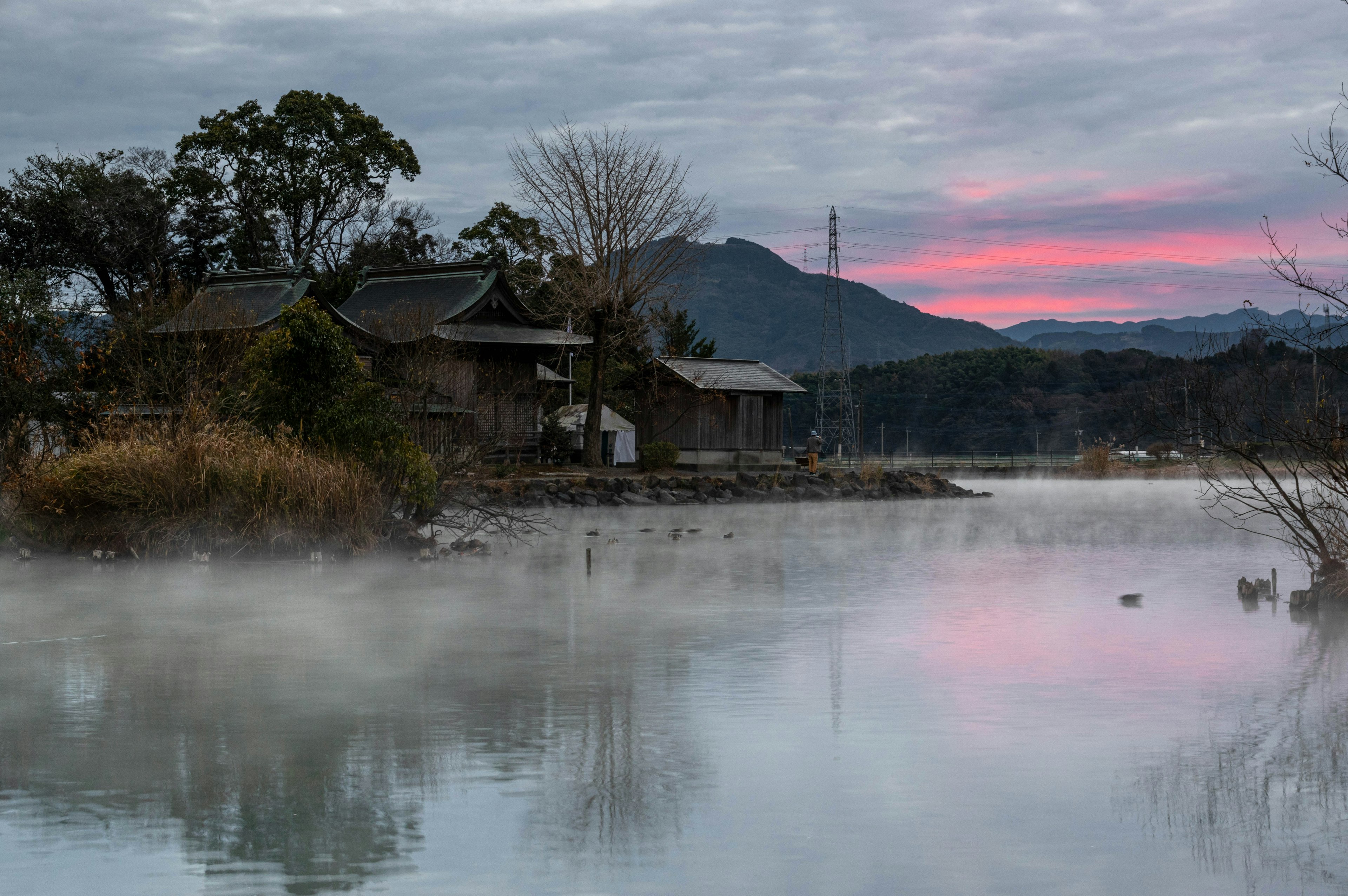 Escena serena junto al lago con casas antiguas y niebla