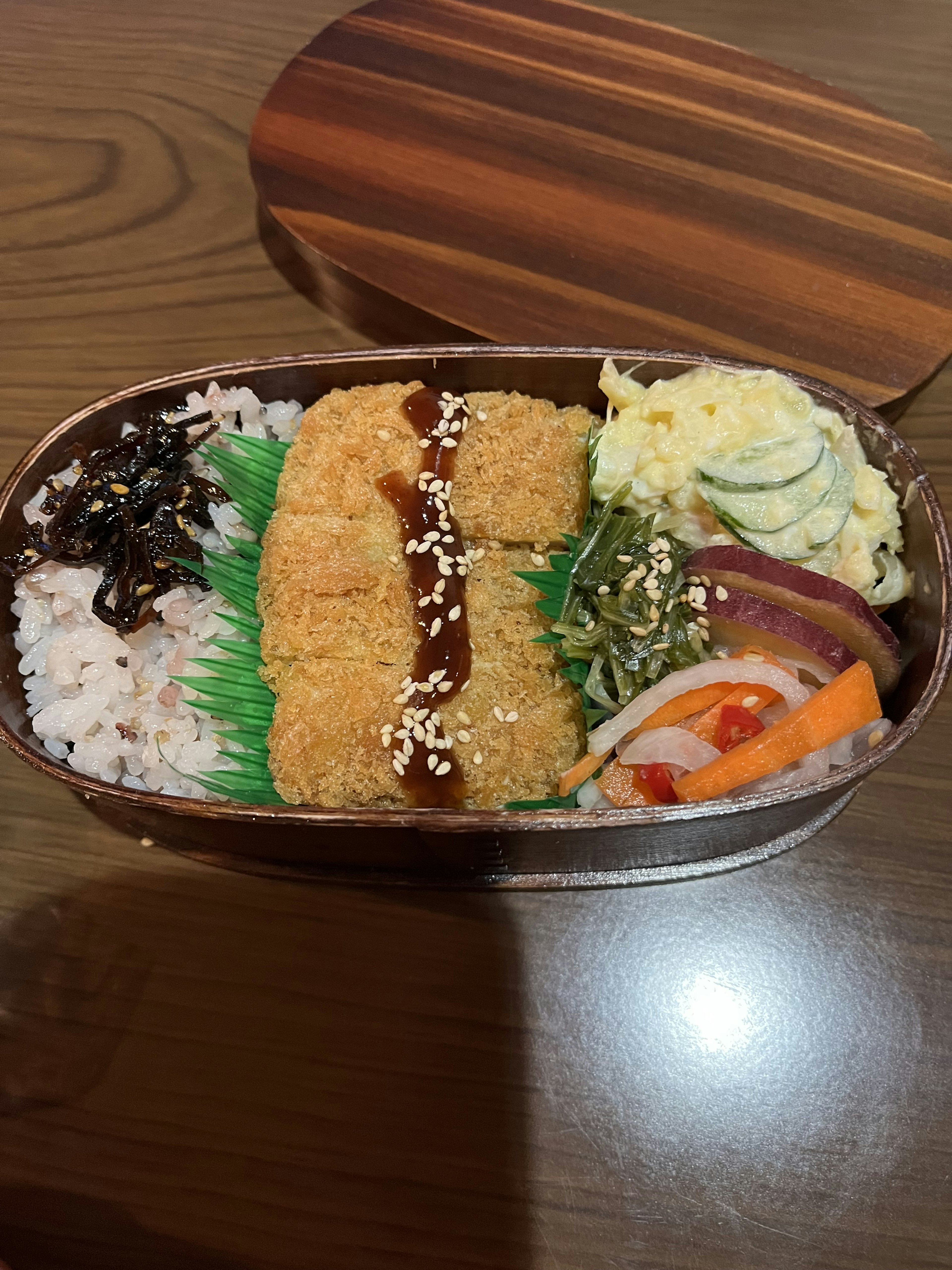 Image of a bento box containing rice, fried chicken, vegetable salad, and tamagoyaki