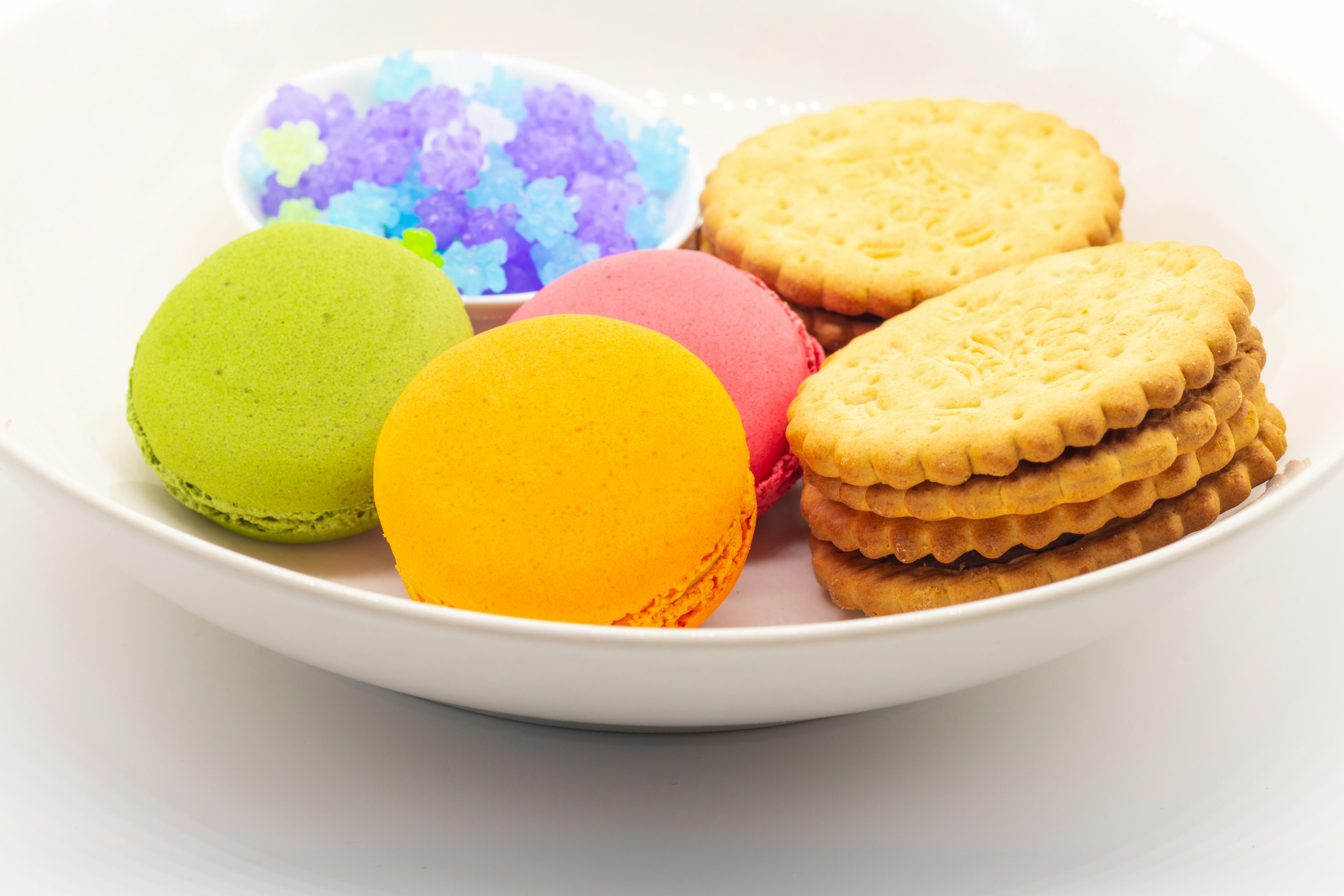 Colorful macarons and crisp cookies arranged in a white bowl