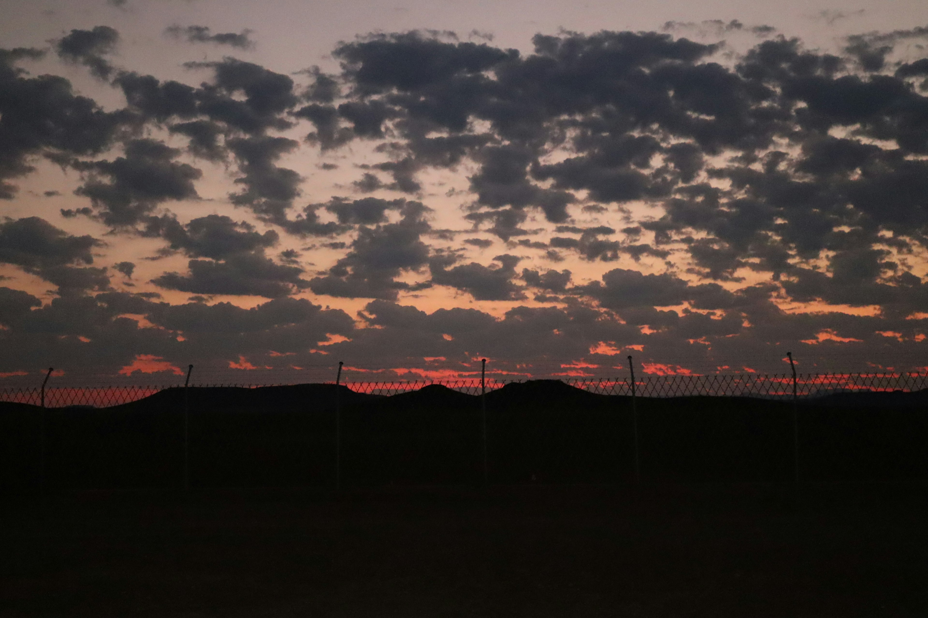 Silhouette von Bergen gegen einen mit Wolken gefüllten Sonnenuntergangshimmel