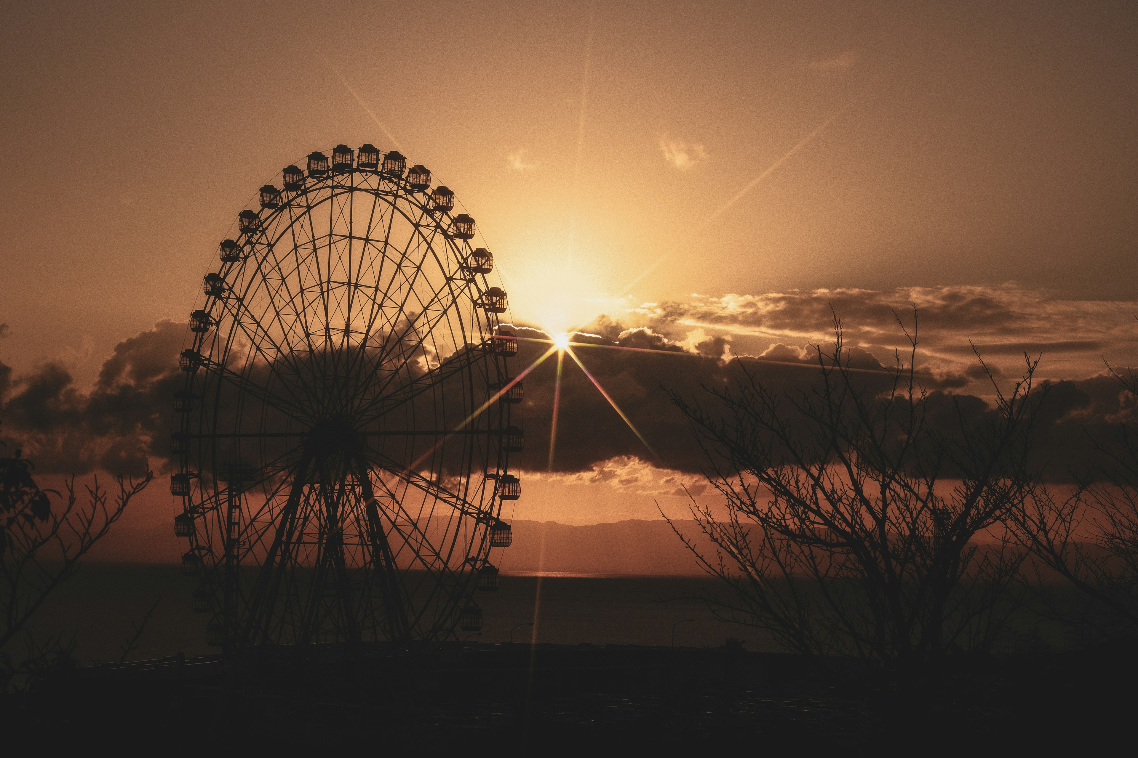 Silhouette of a Ferris wheel against a sunset