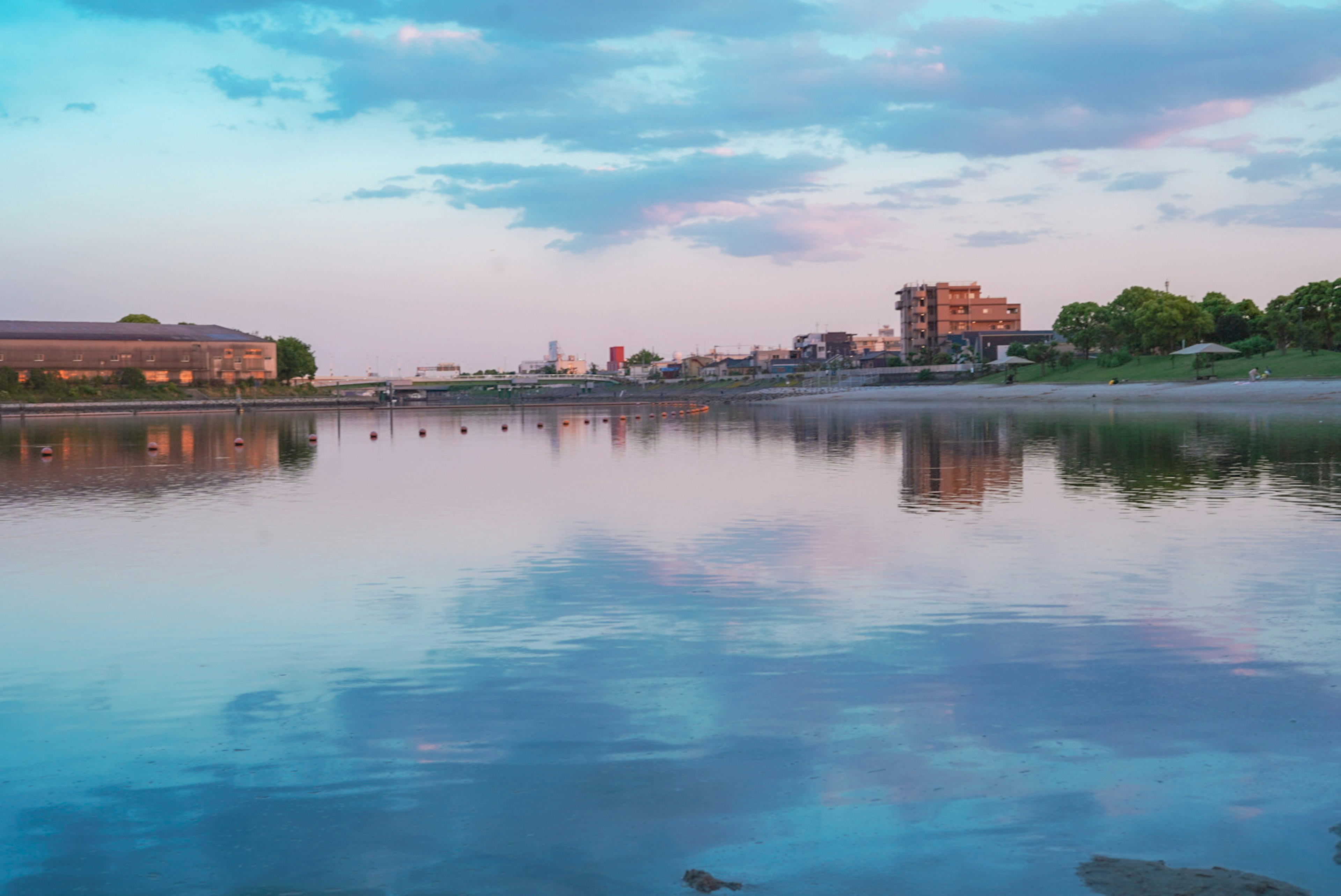 Calm water reflecting blue sky and building silhouettes