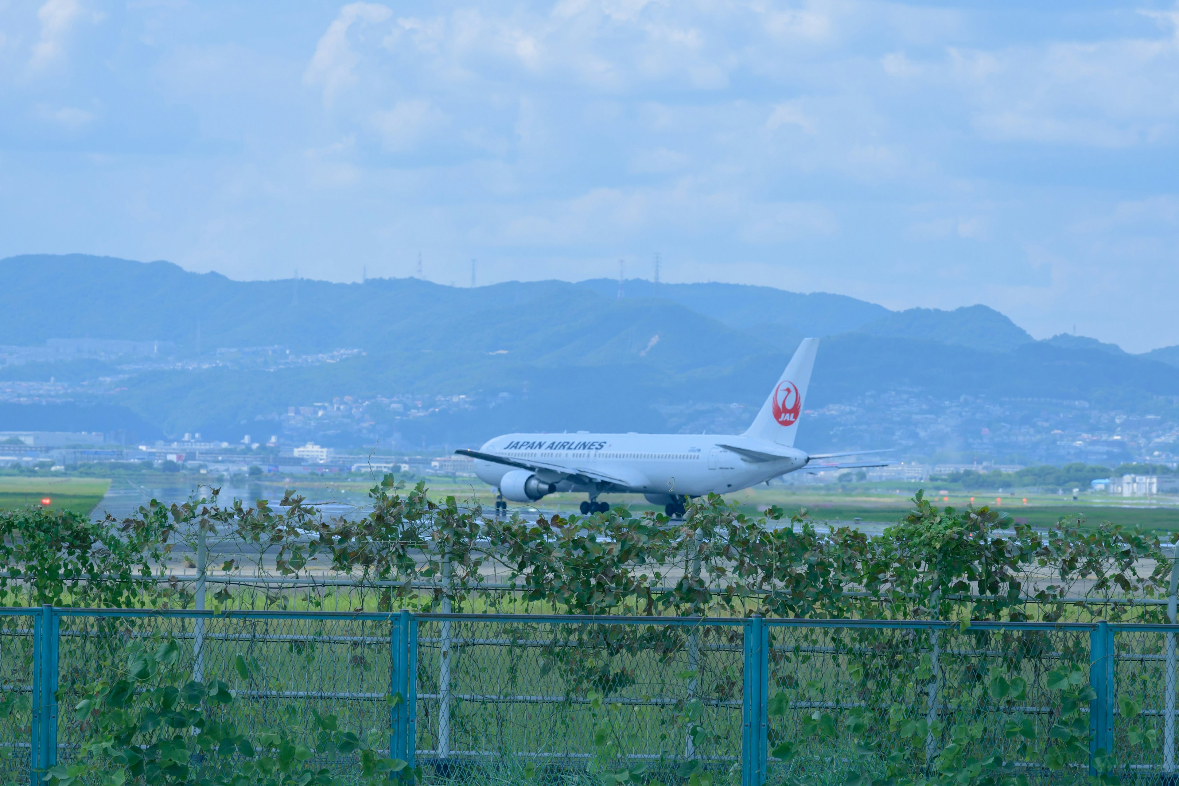 Airplane taxiing on runway with mountains in background