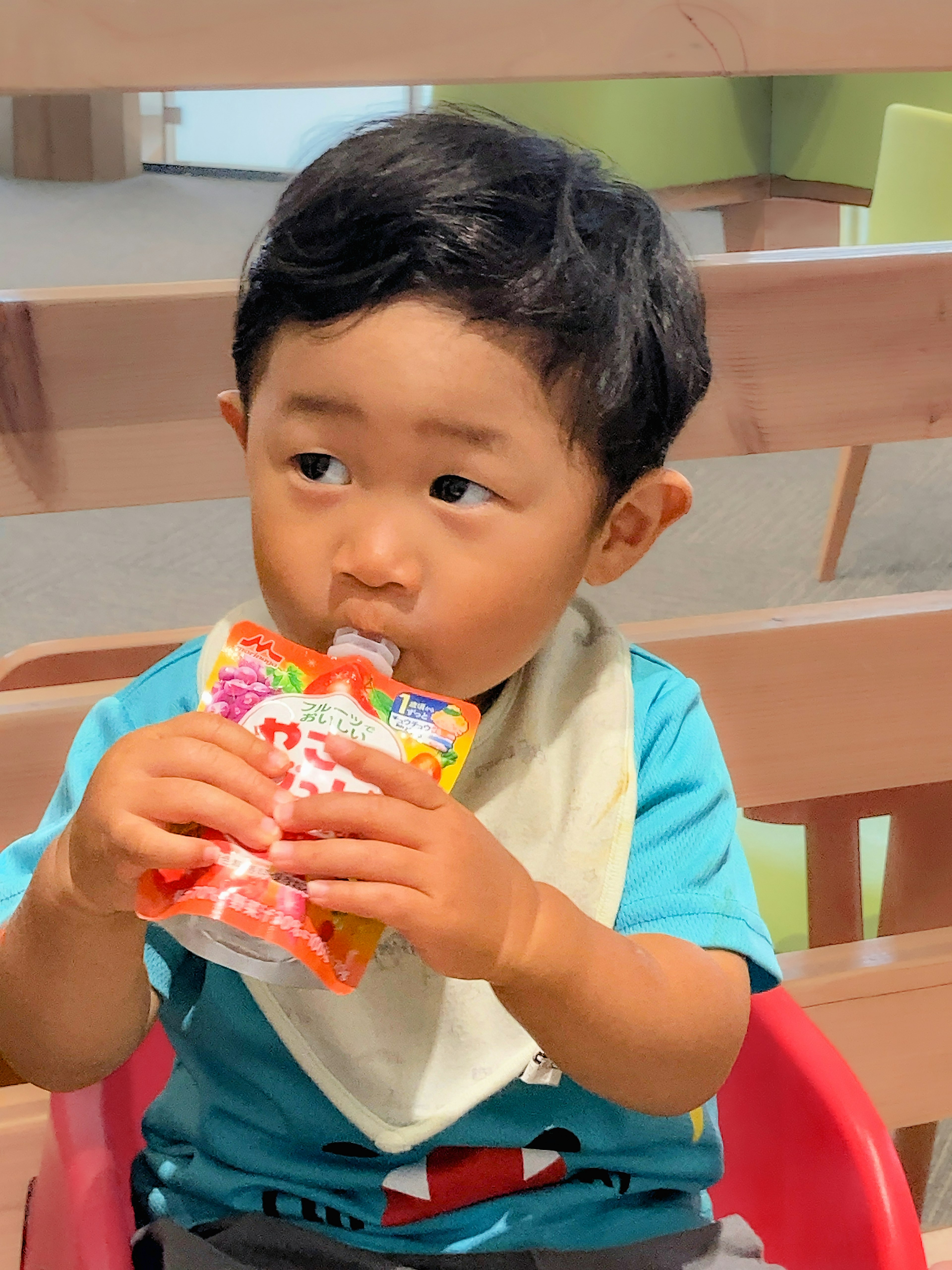 A young boy drinking from a snack pouch