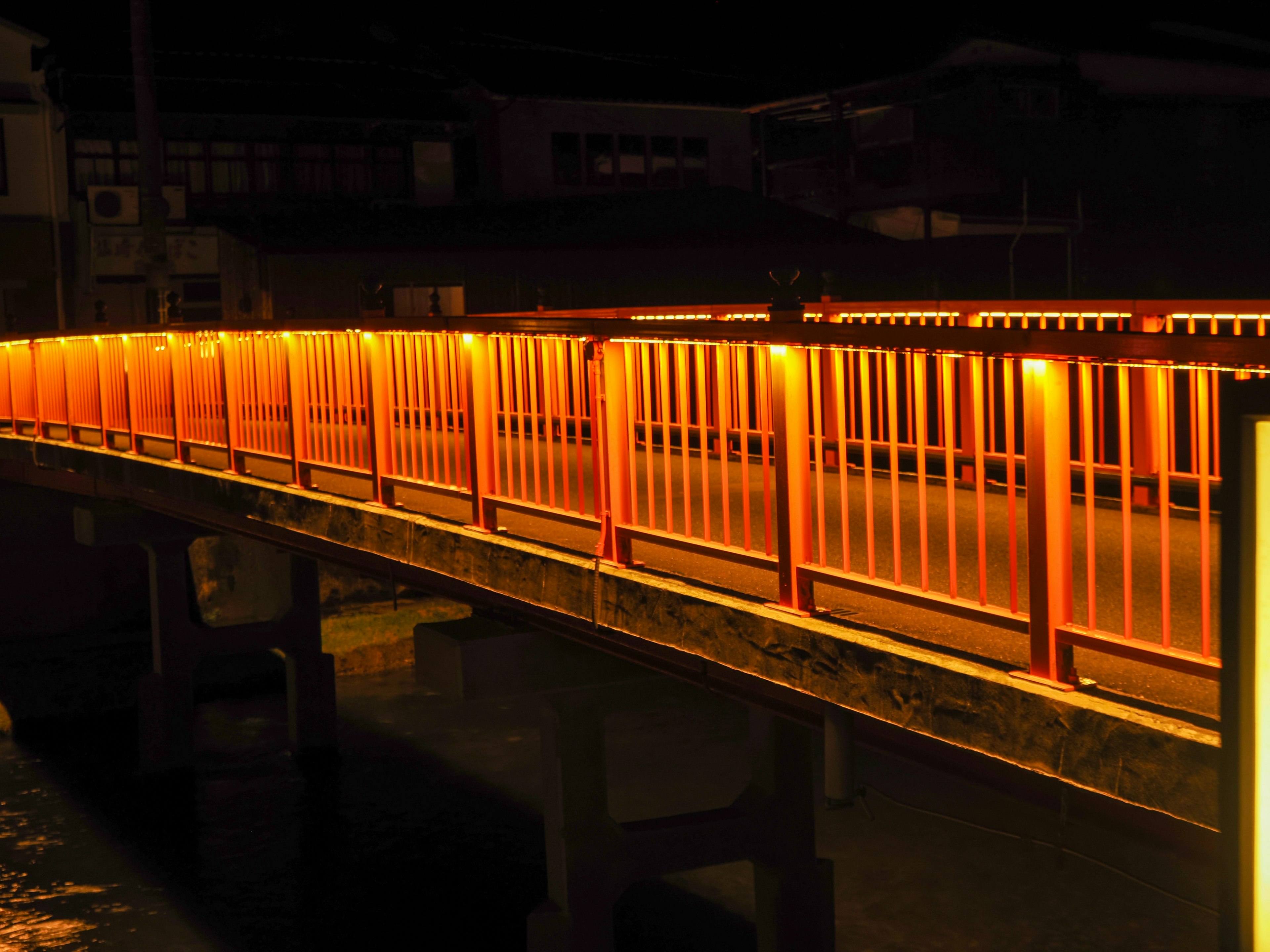 Jembatan oranye terang di atas sungai di malam hari