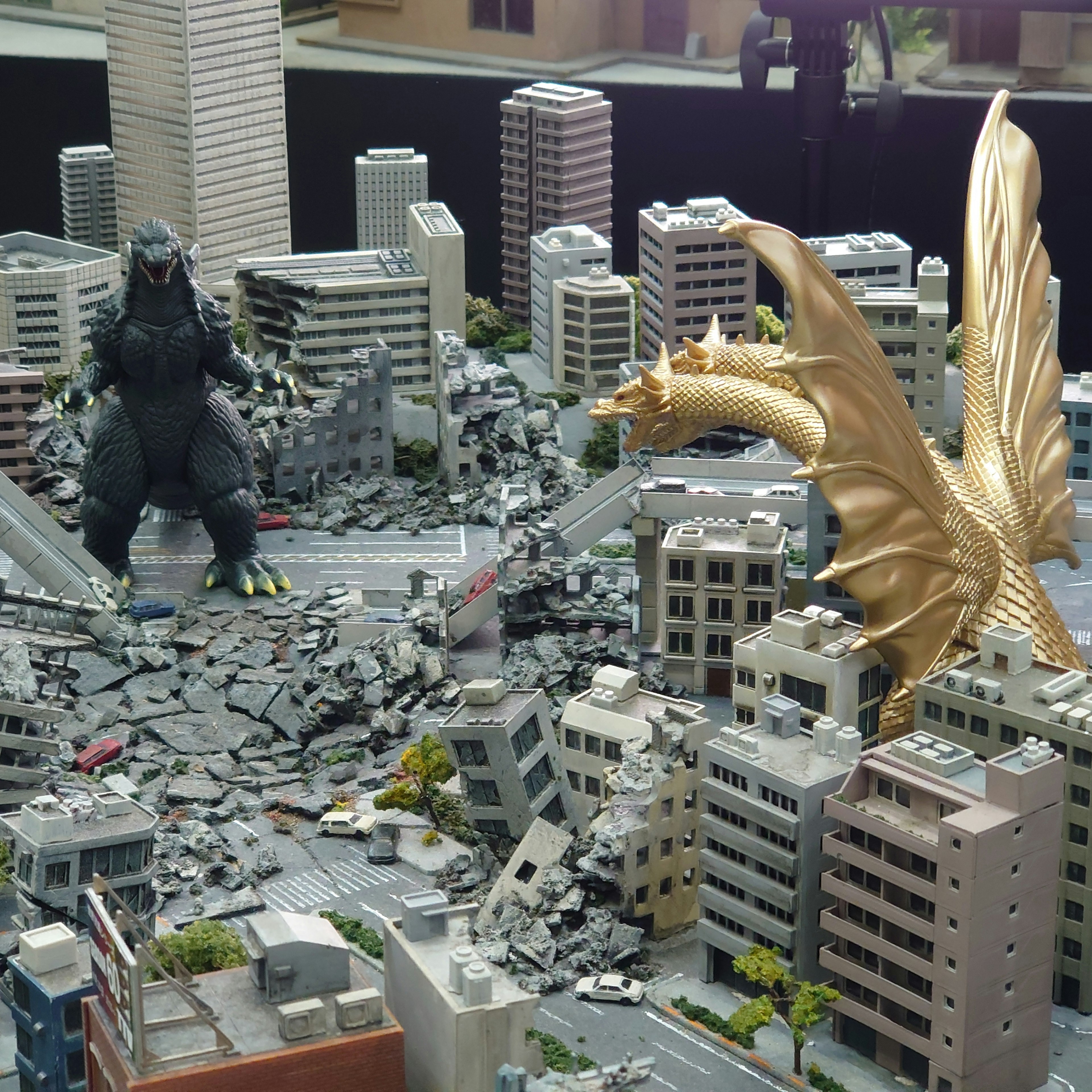 Godzilla e King Ghidorah che si affrontano in un modello di città distrutta