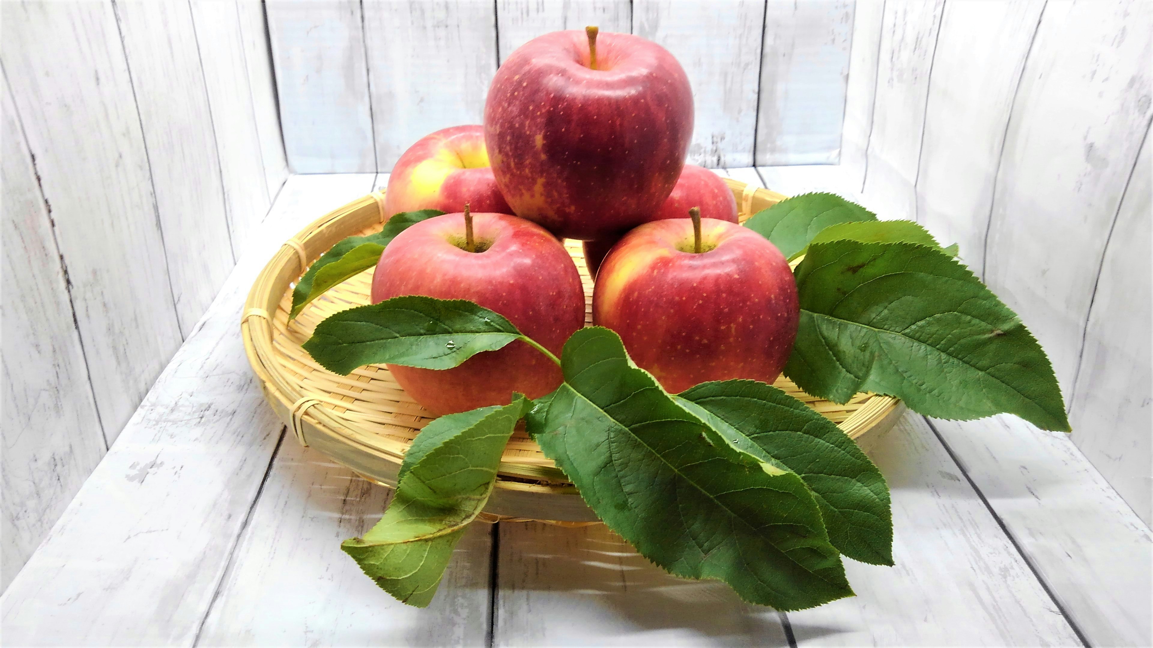 A basket of red apples with green leaves