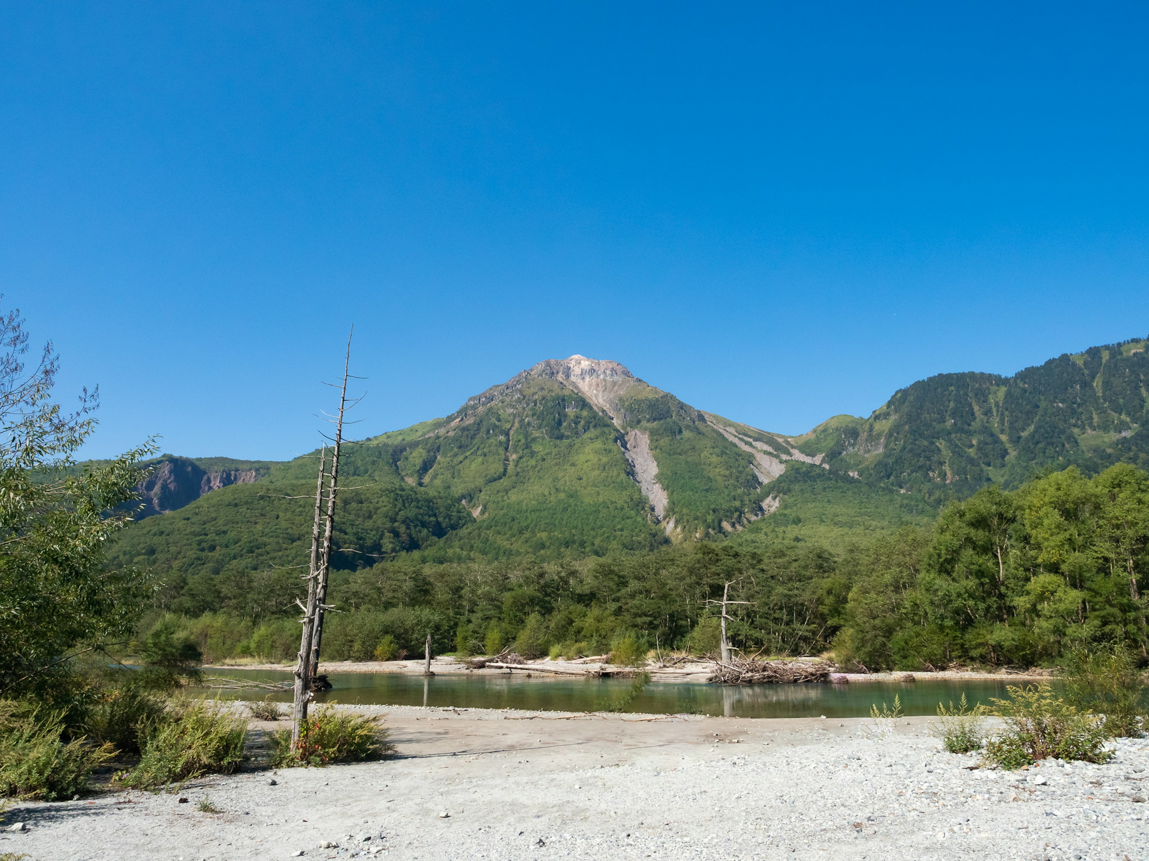 青空の下に広がる山々と川の風景