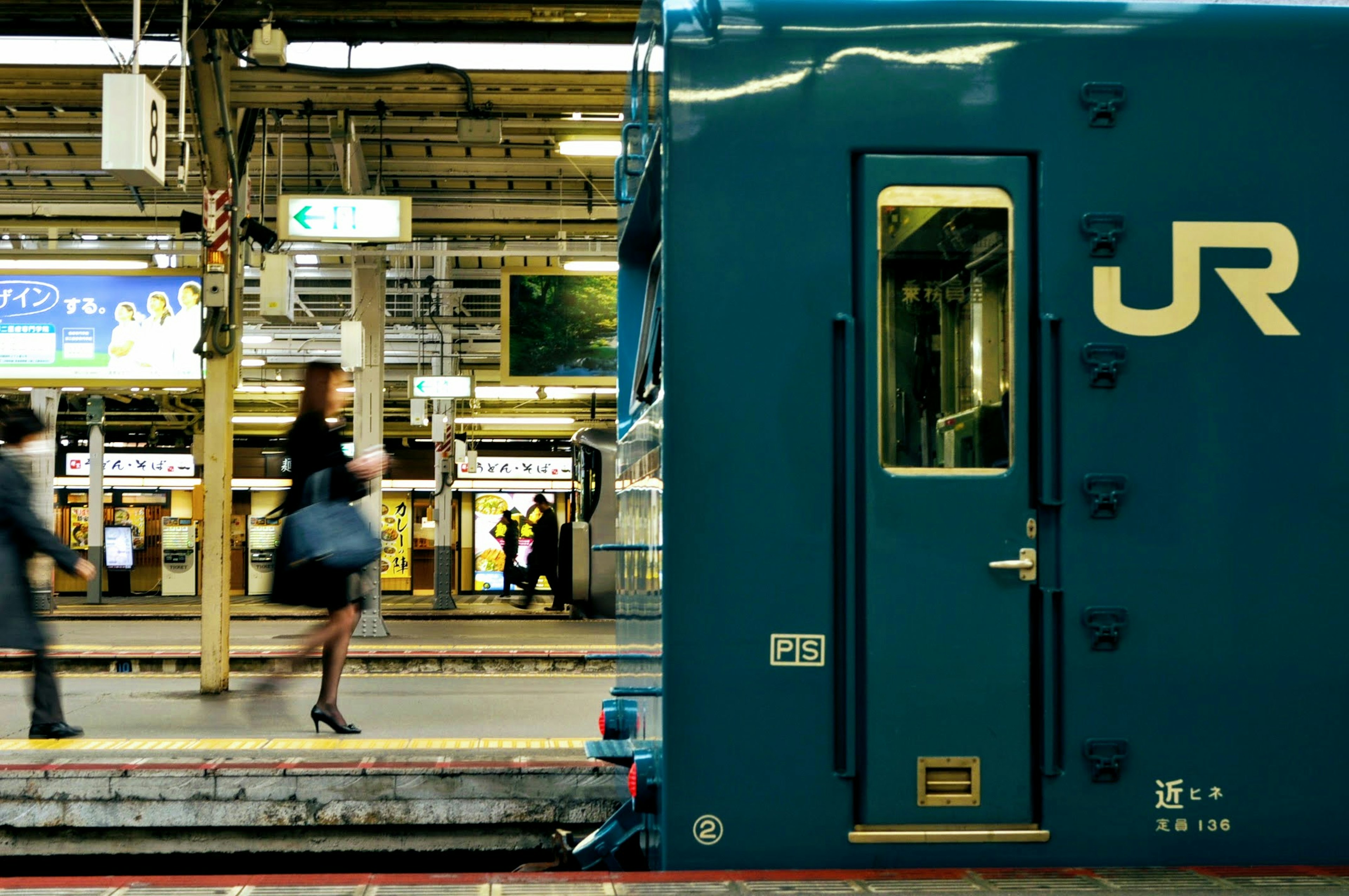 Blue JR train with people walking at the station