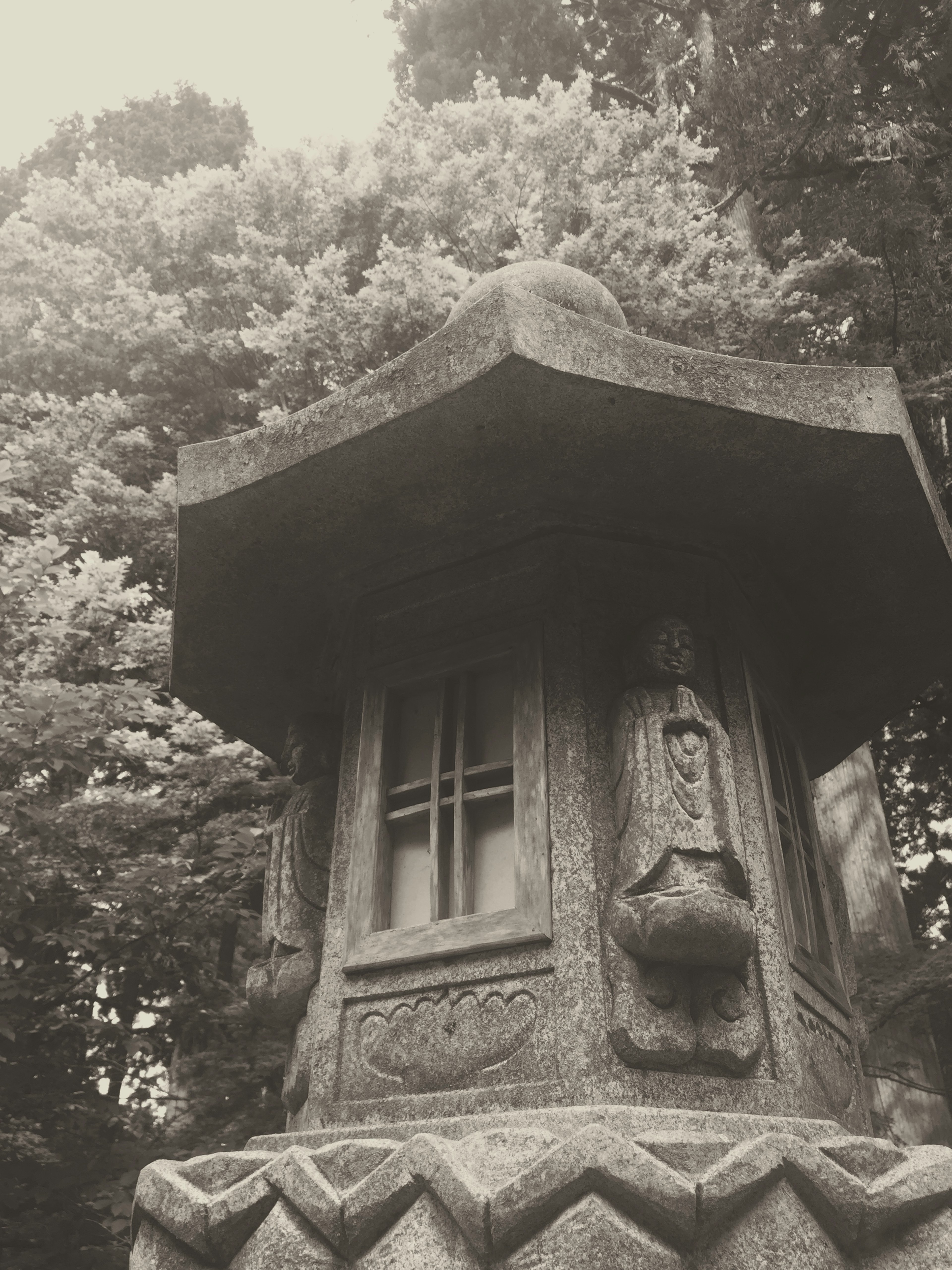 Black and white image of a stone lantern surrounded by trees