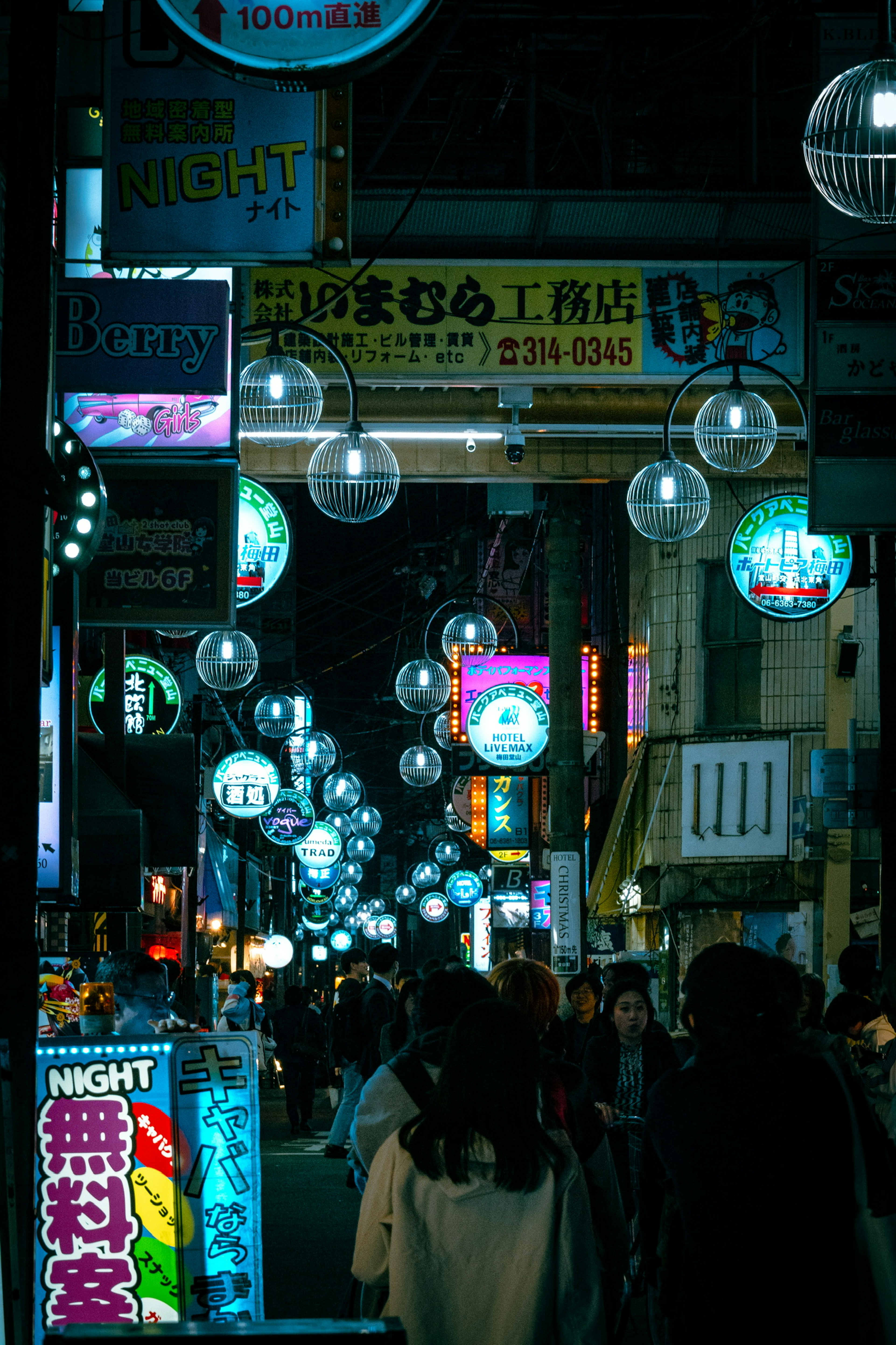 Calle nocturna con faroles brillantes y letreros coloridos en un distrito comercial