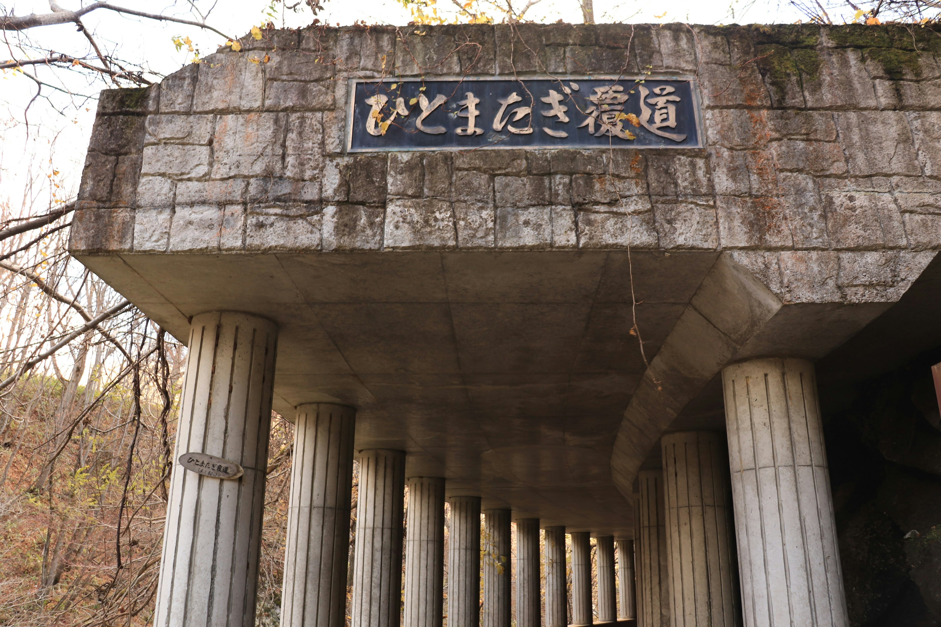 Antiguo arco de concreto con columnas y un cartel arriba