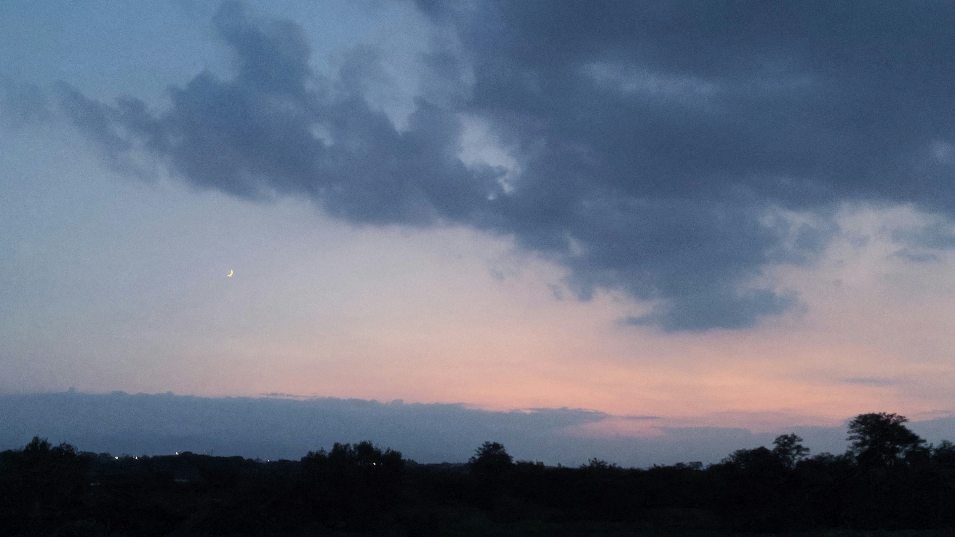 夕焼けの空に浮かぶ雲と薄明かりの月