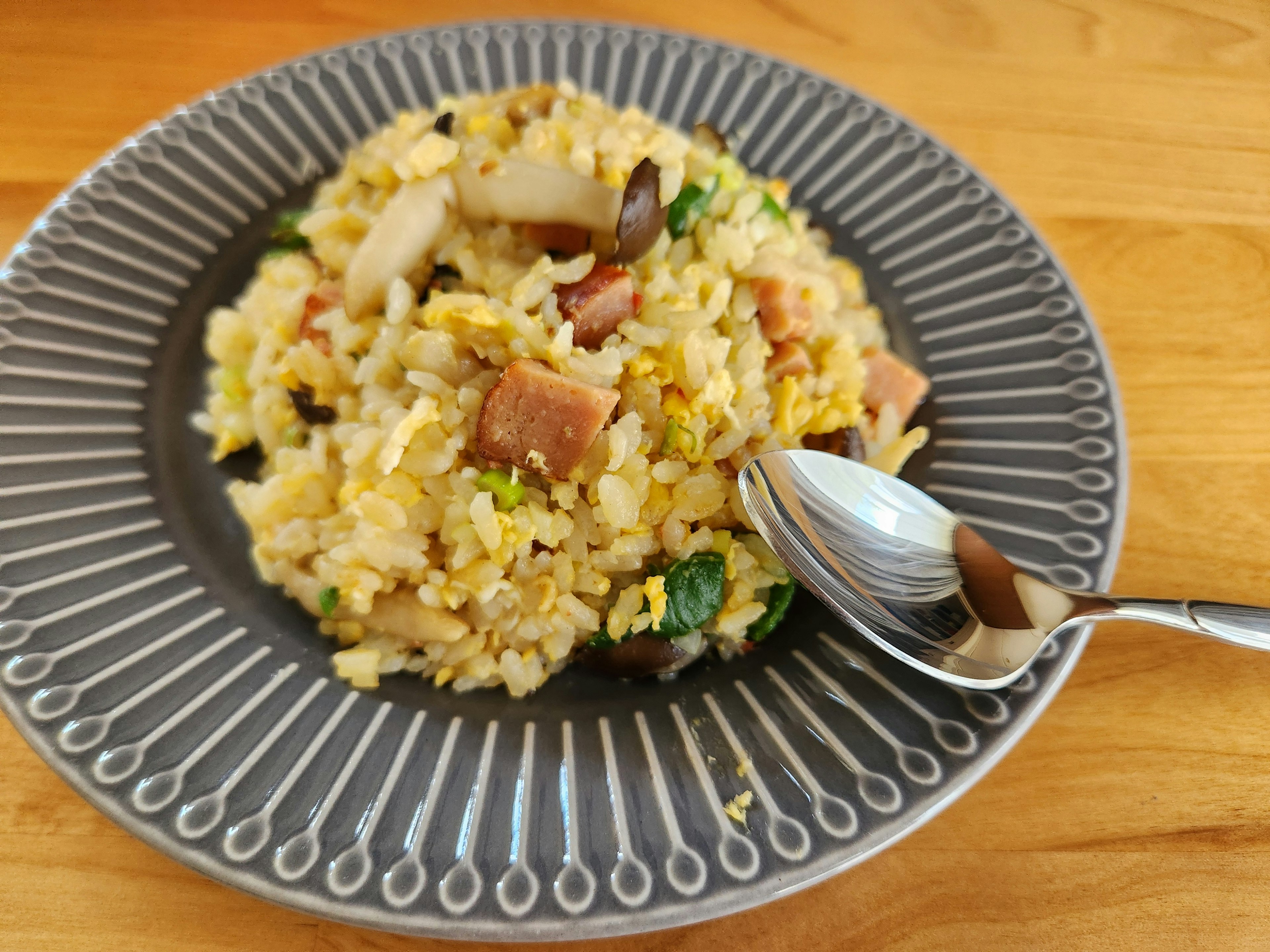 Delicious fried rice served on a gray plate with a spoon