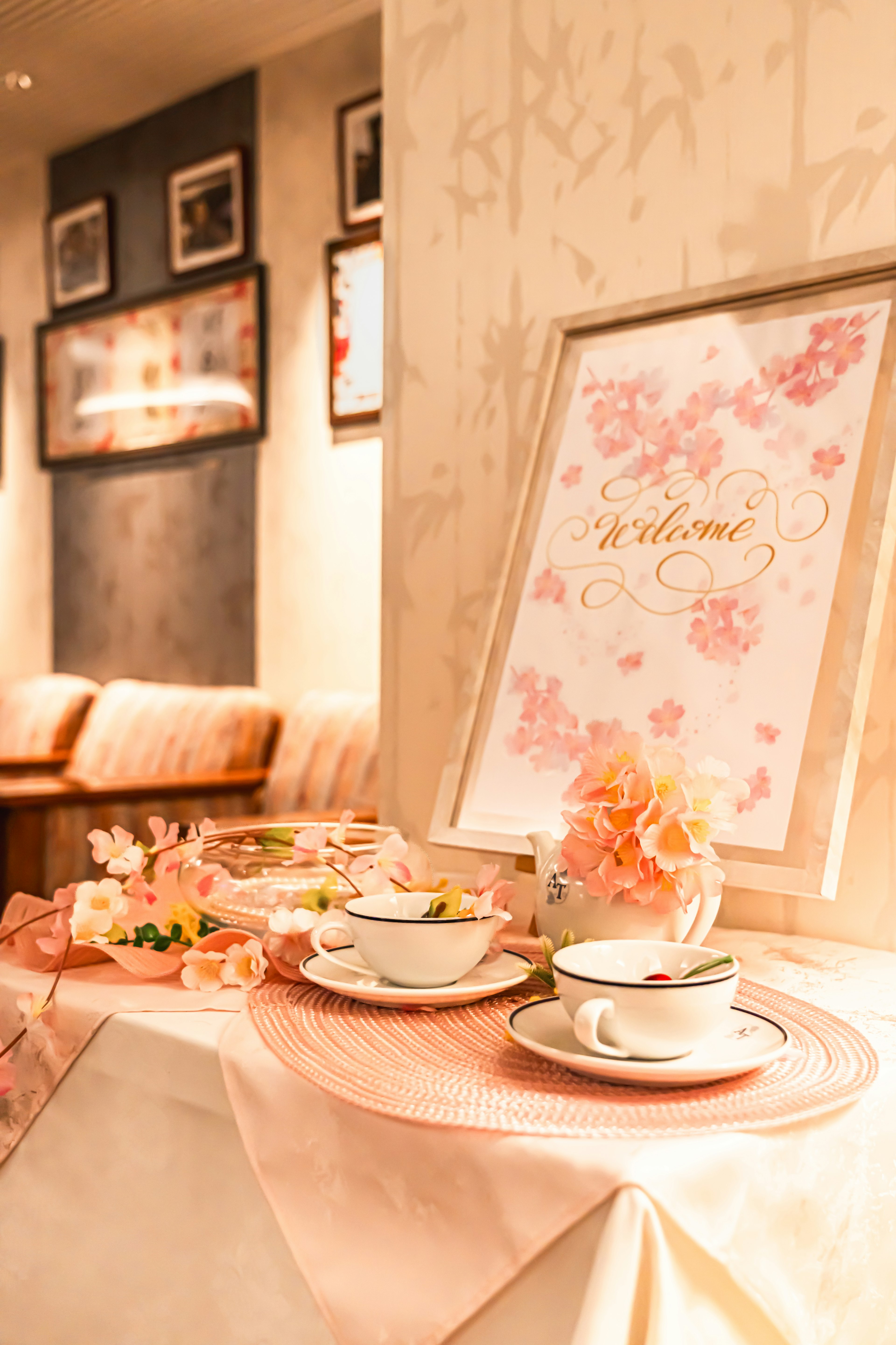 Una mesa bellamente decorada con un letrero de bienvenida con flores de cerezo y un juego de té