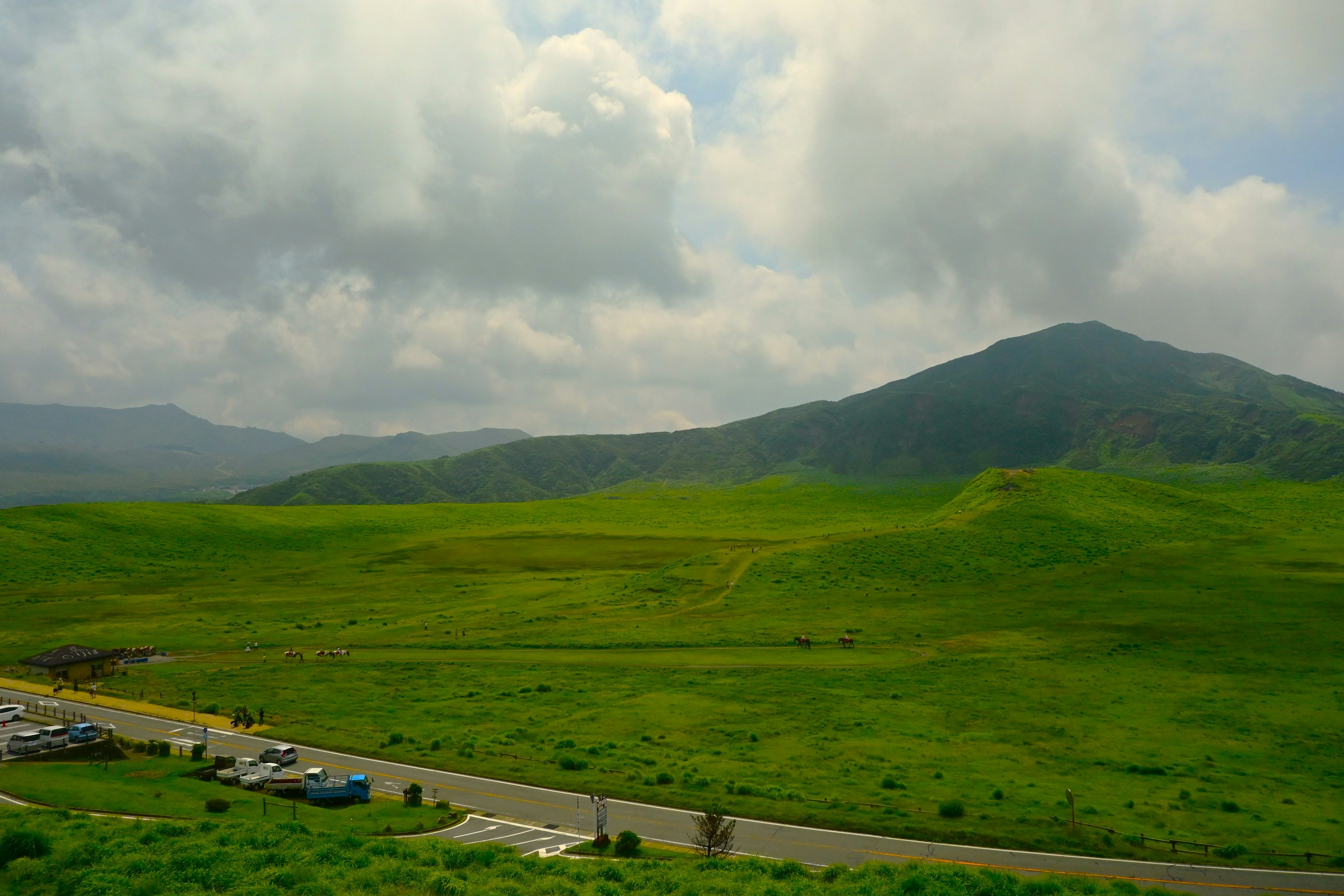 緑豊かな草原と山々の風景 駐車場に車が並ぶ