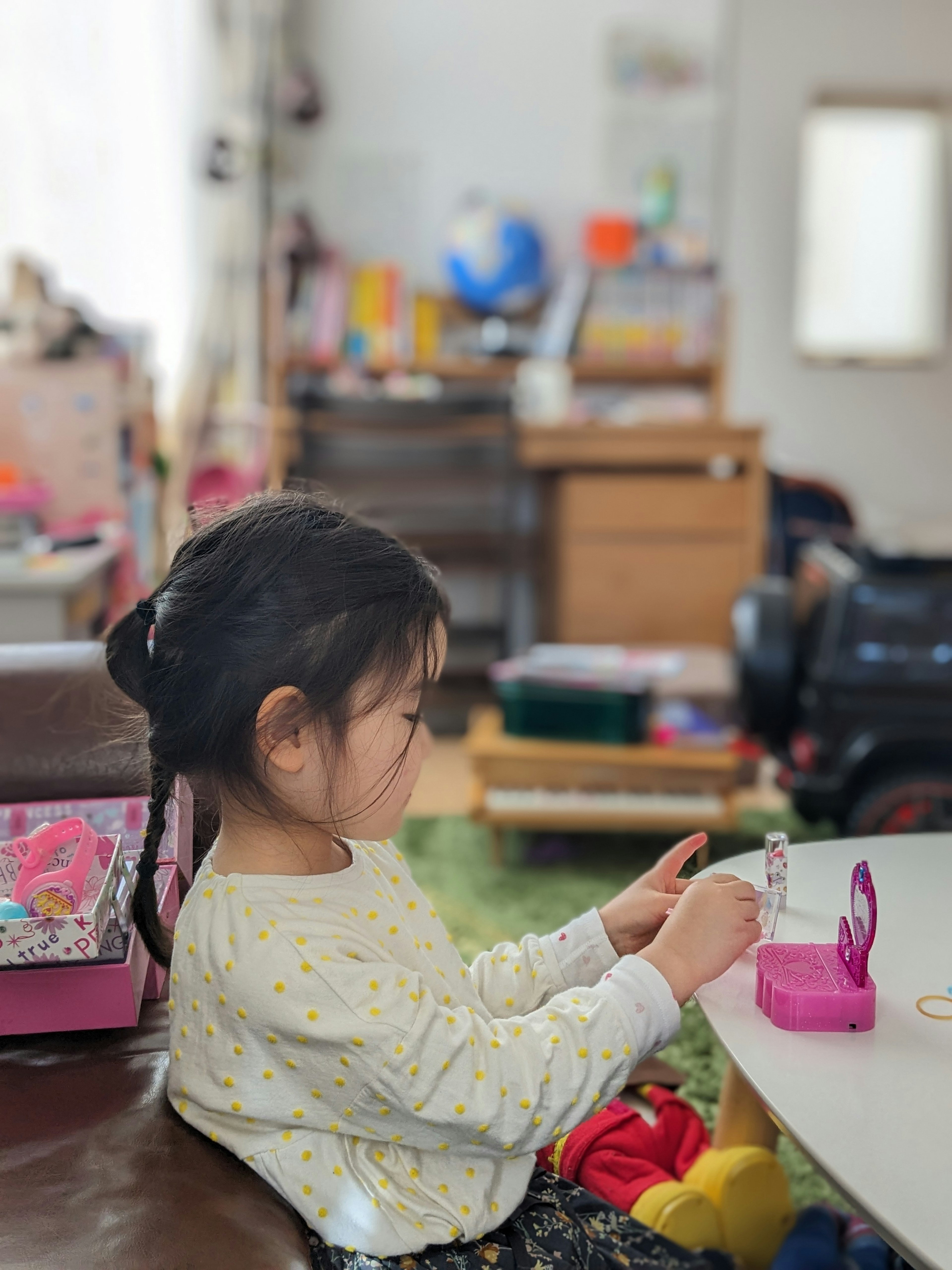 子供がテーブルで遊んでいる様子 背景にはおもちゃや家具が見える