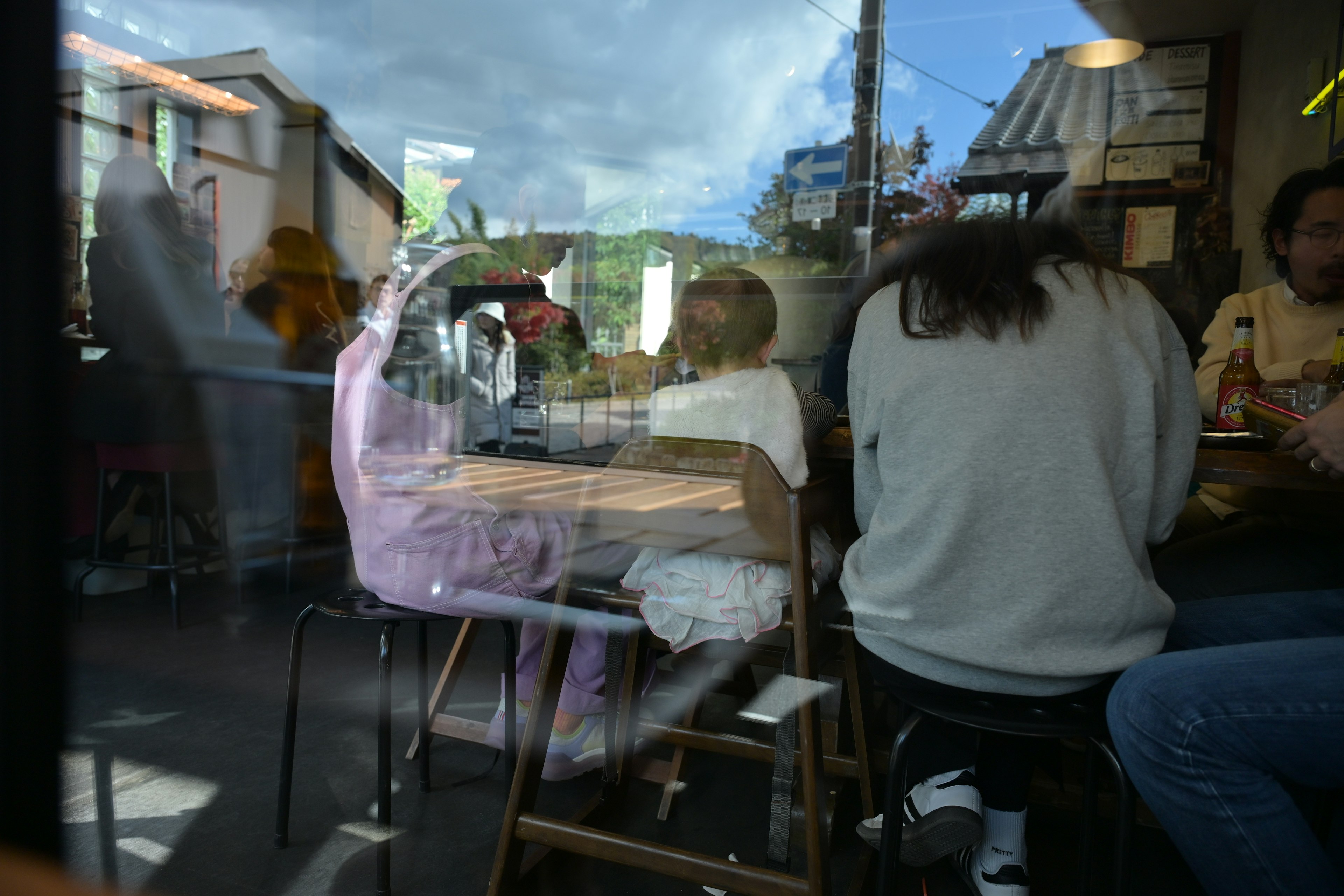 カフェの窓越しに見える人々と青空