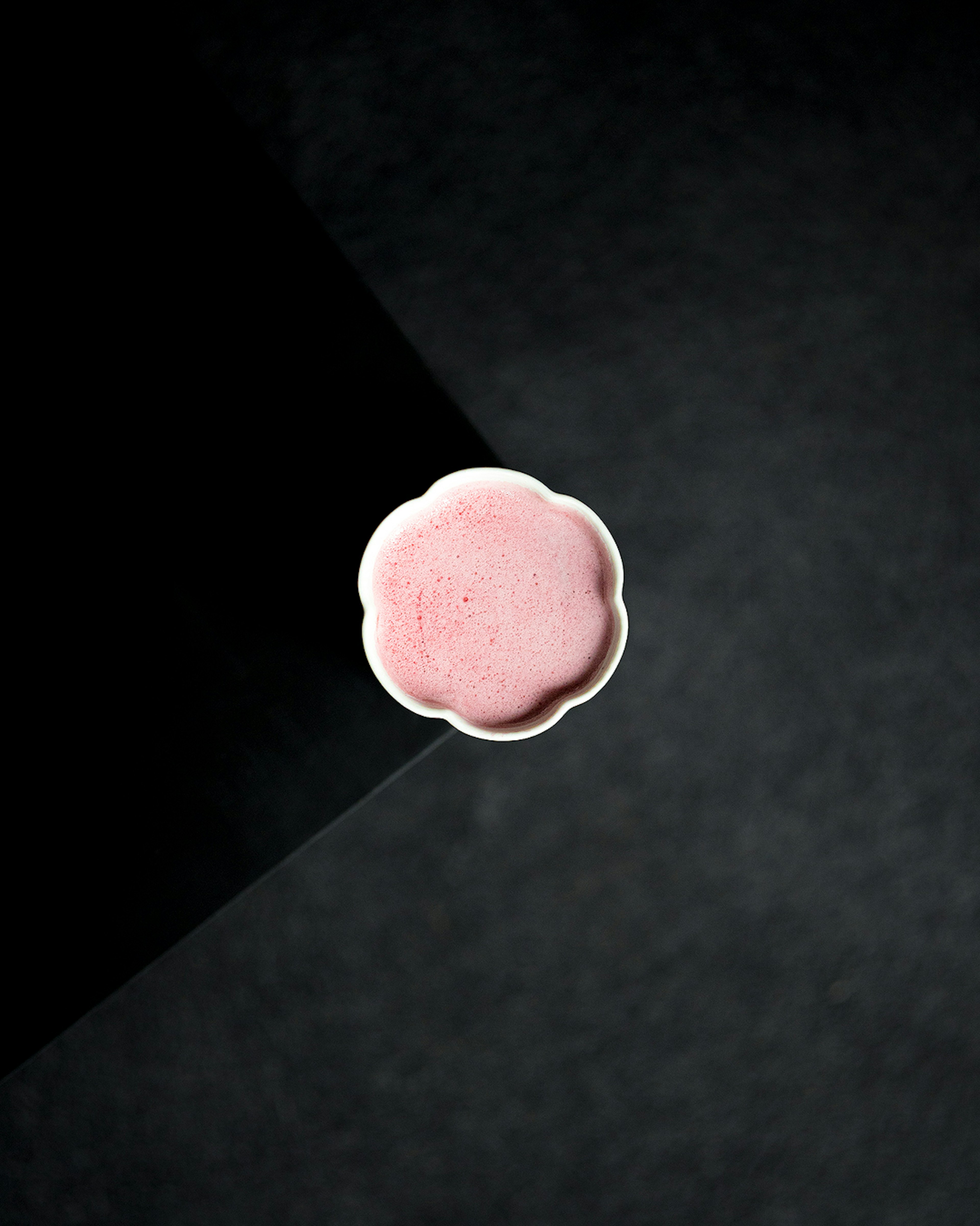 Draufsicht auf einen rosa Macaron auf schwarzem Hintergrund