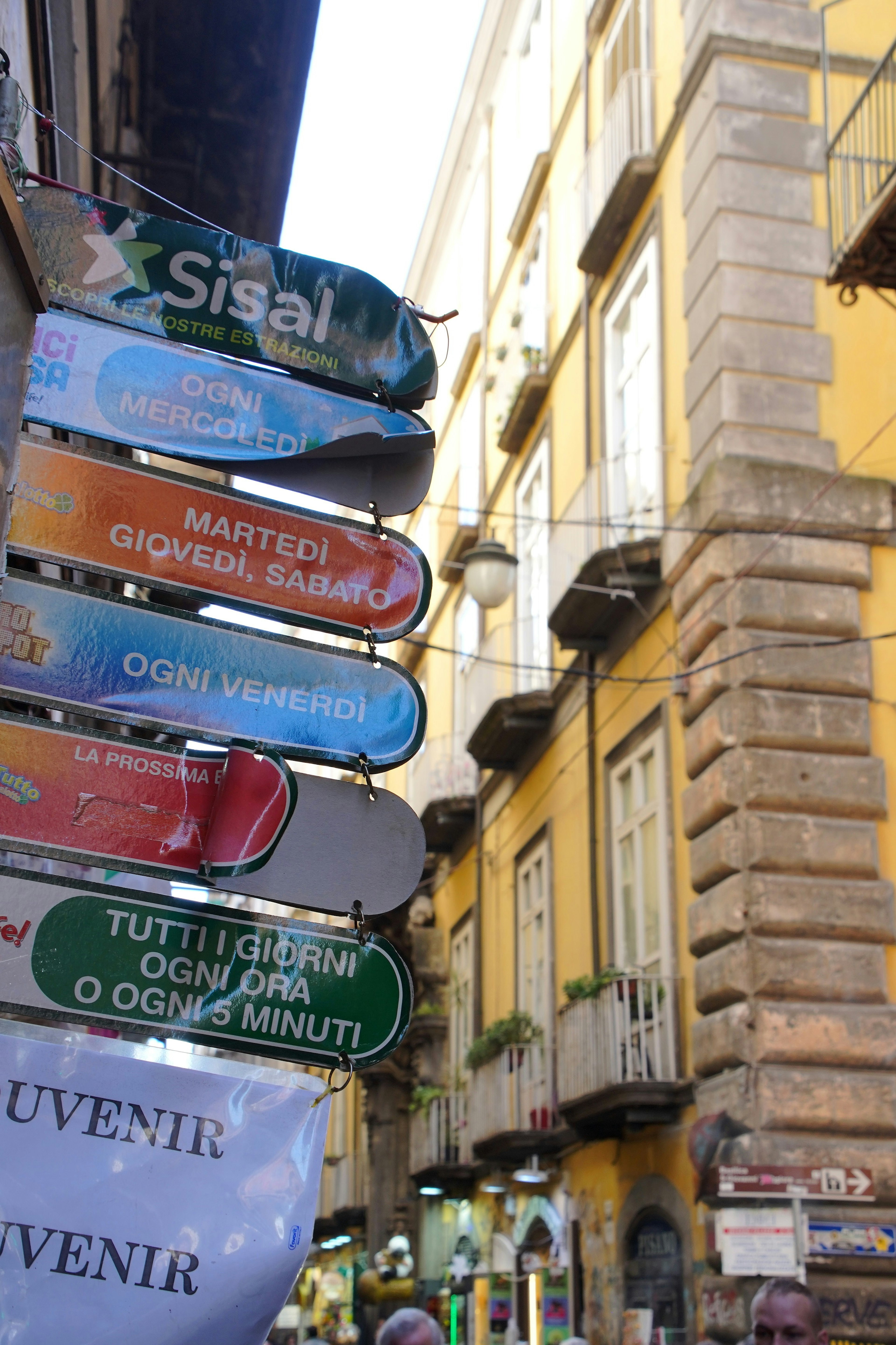 Señales coloridas en una calle estrecha de Nápoles con edificios históricos