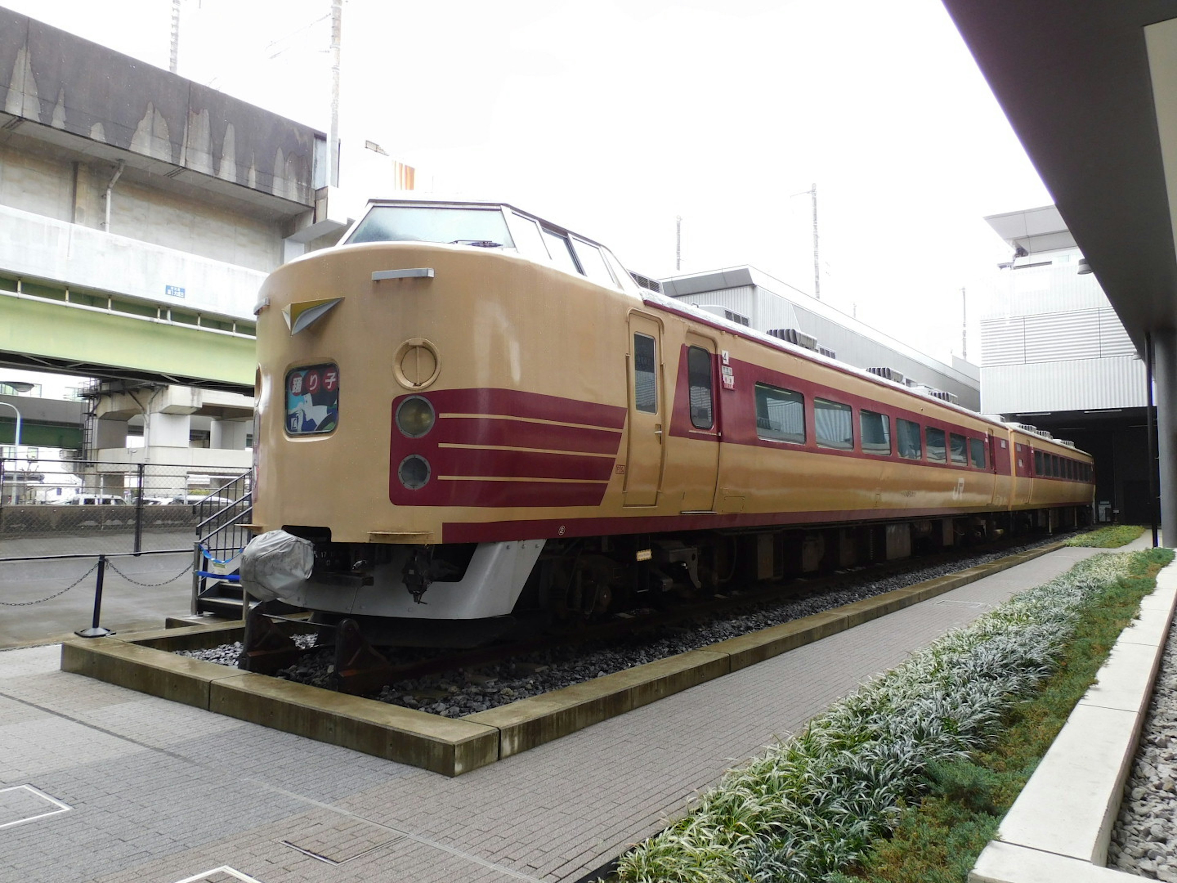 Kereta ekspres Jepang dengan desain merah dan krem dipajang di luar