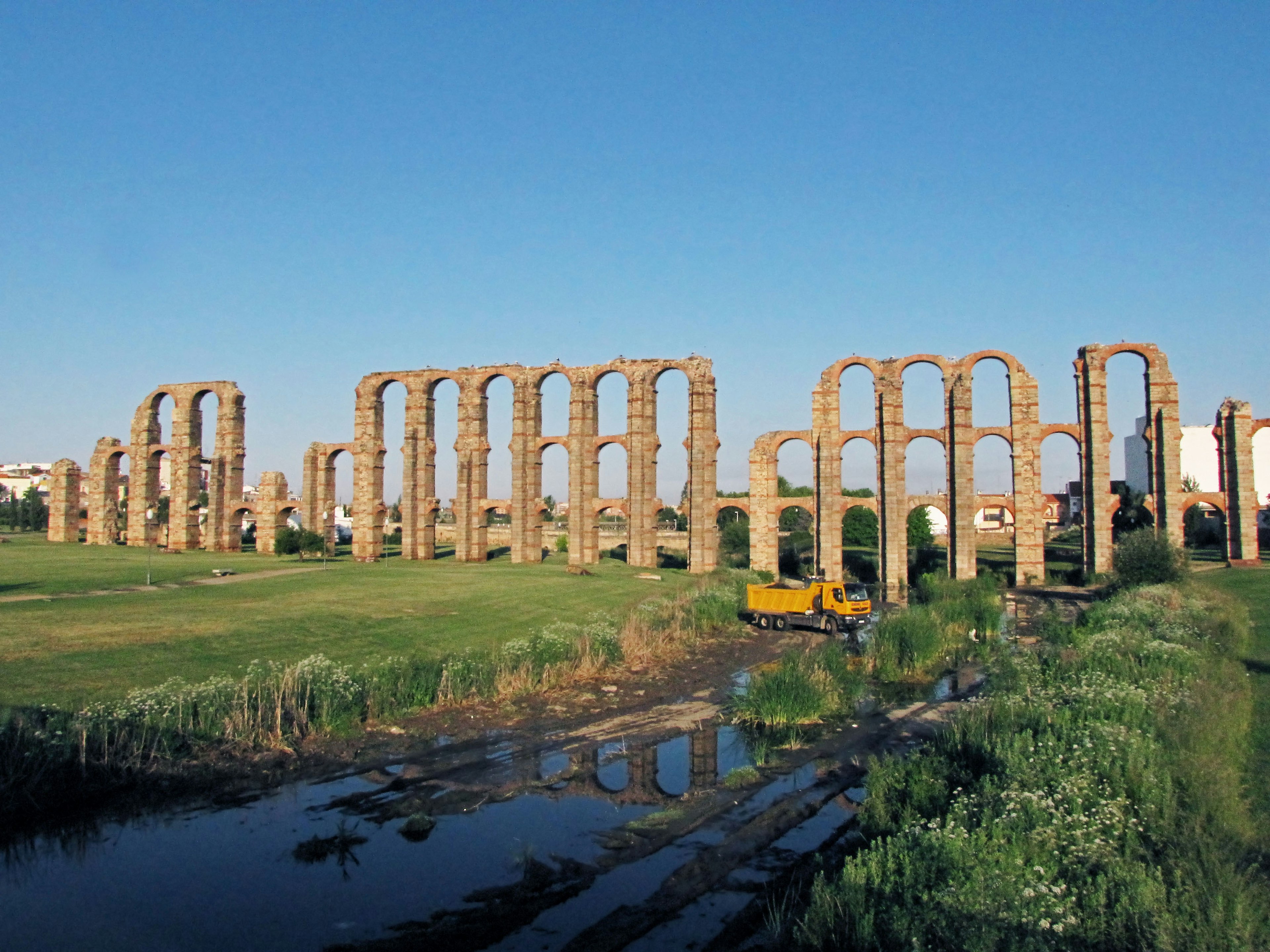 Di tích aqueduct cổ dưới bầu trời xanh với thảm thực vật xung quanh