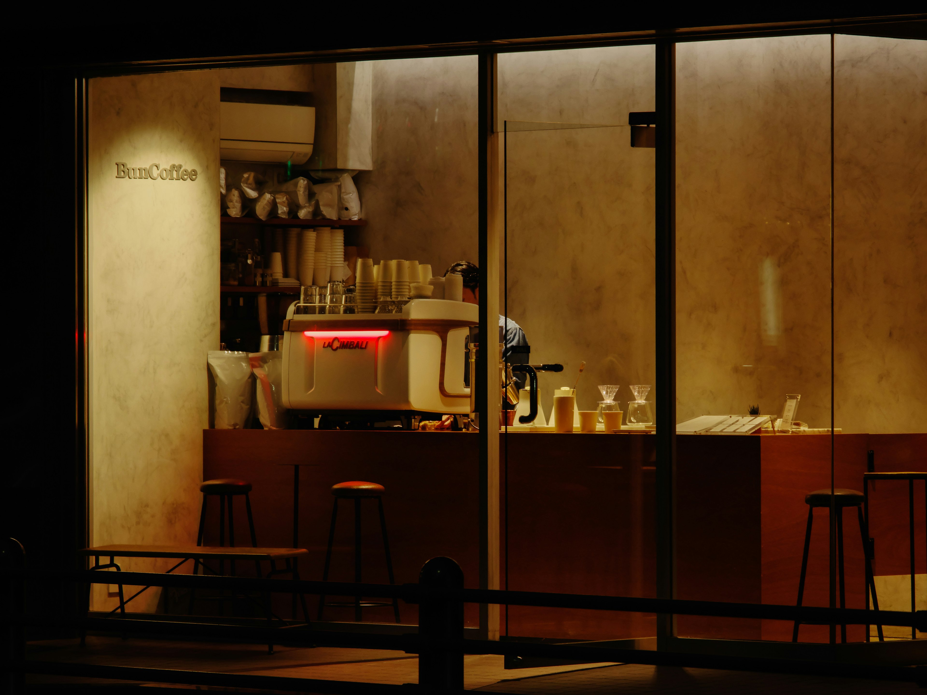 Imagen del interior de un café por la noche con iluminación cálida y una máquina de café