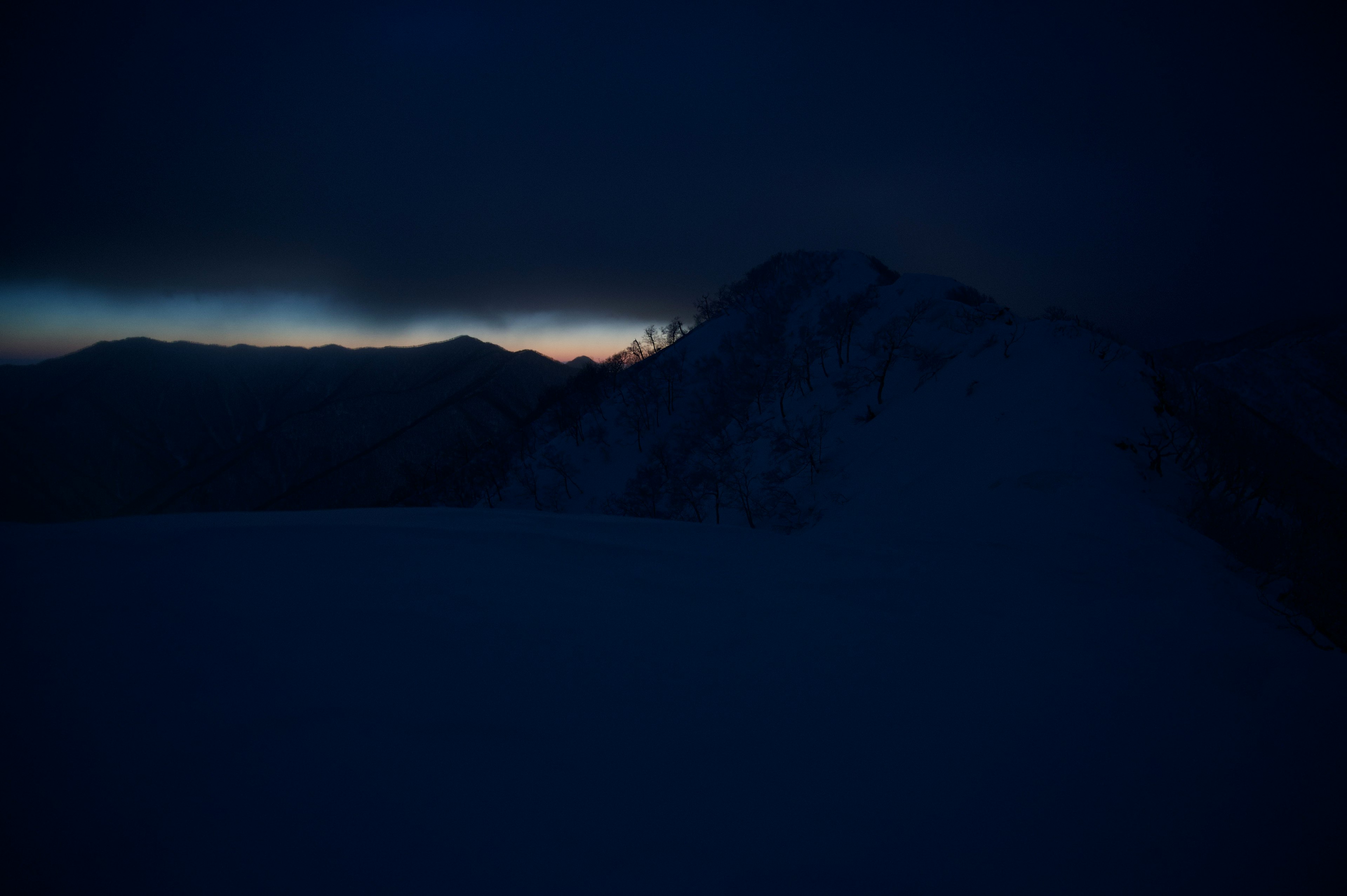 Dark mountain silhouette with faint horizon light